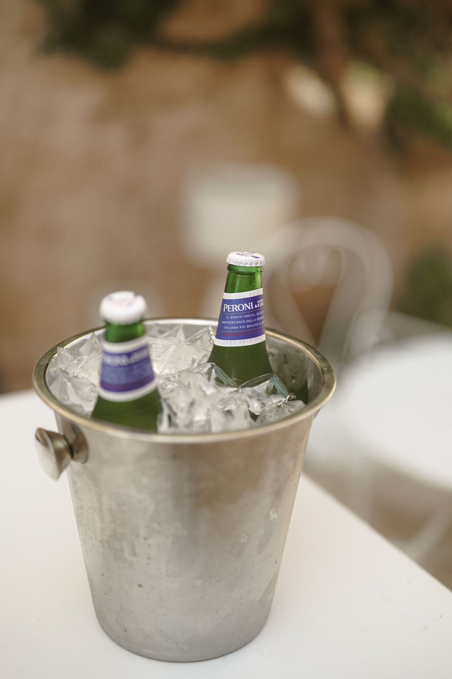 Ice cold beer bottles chilling in a silver champagne bucket filled with ice.