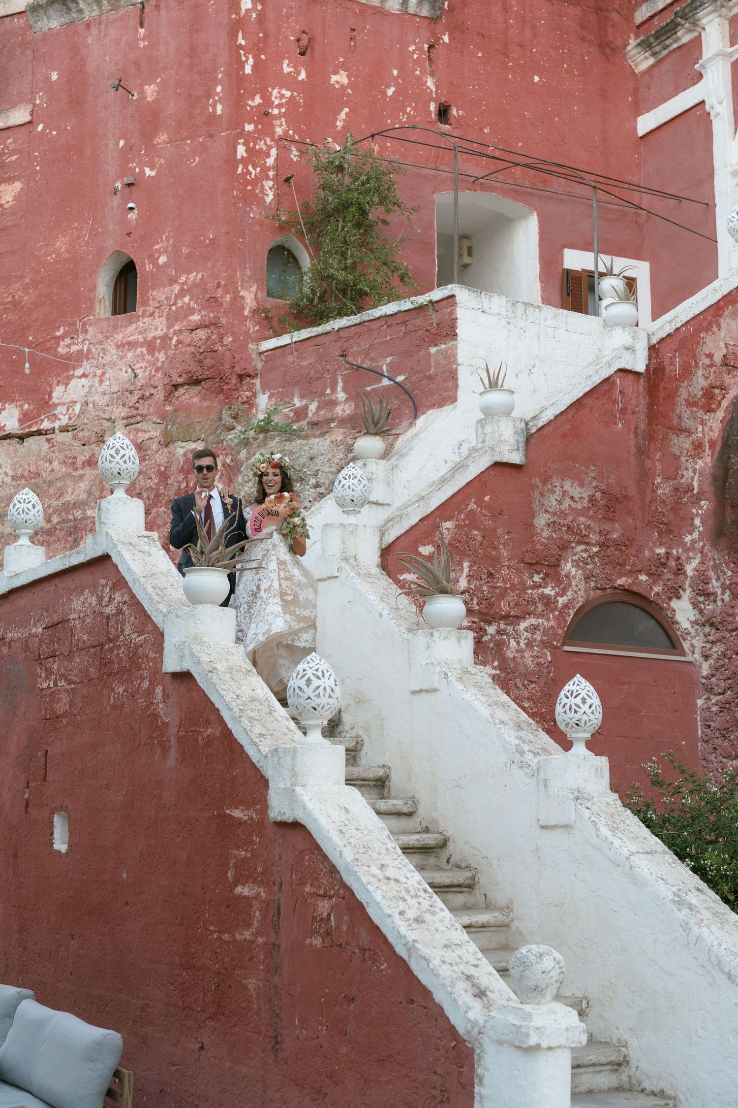 Exterior view of weathered red wall with white concrete staircase.