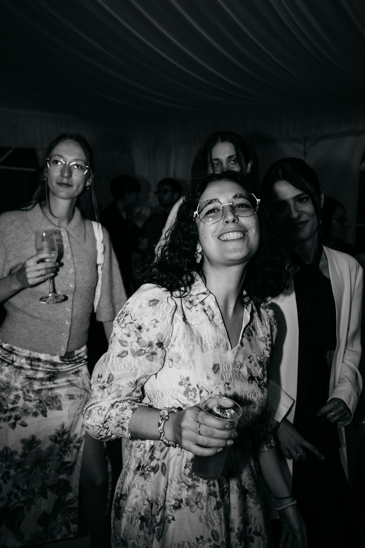 Wedding guests enjoying drinks and dancing at a dimly lit evening reception celebration.