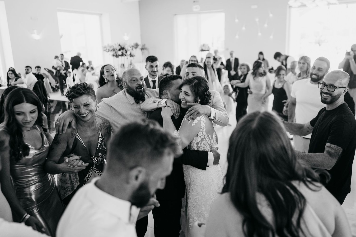 Black and white photo of a crowded wedding reception with guests mingling in an elegant hall.