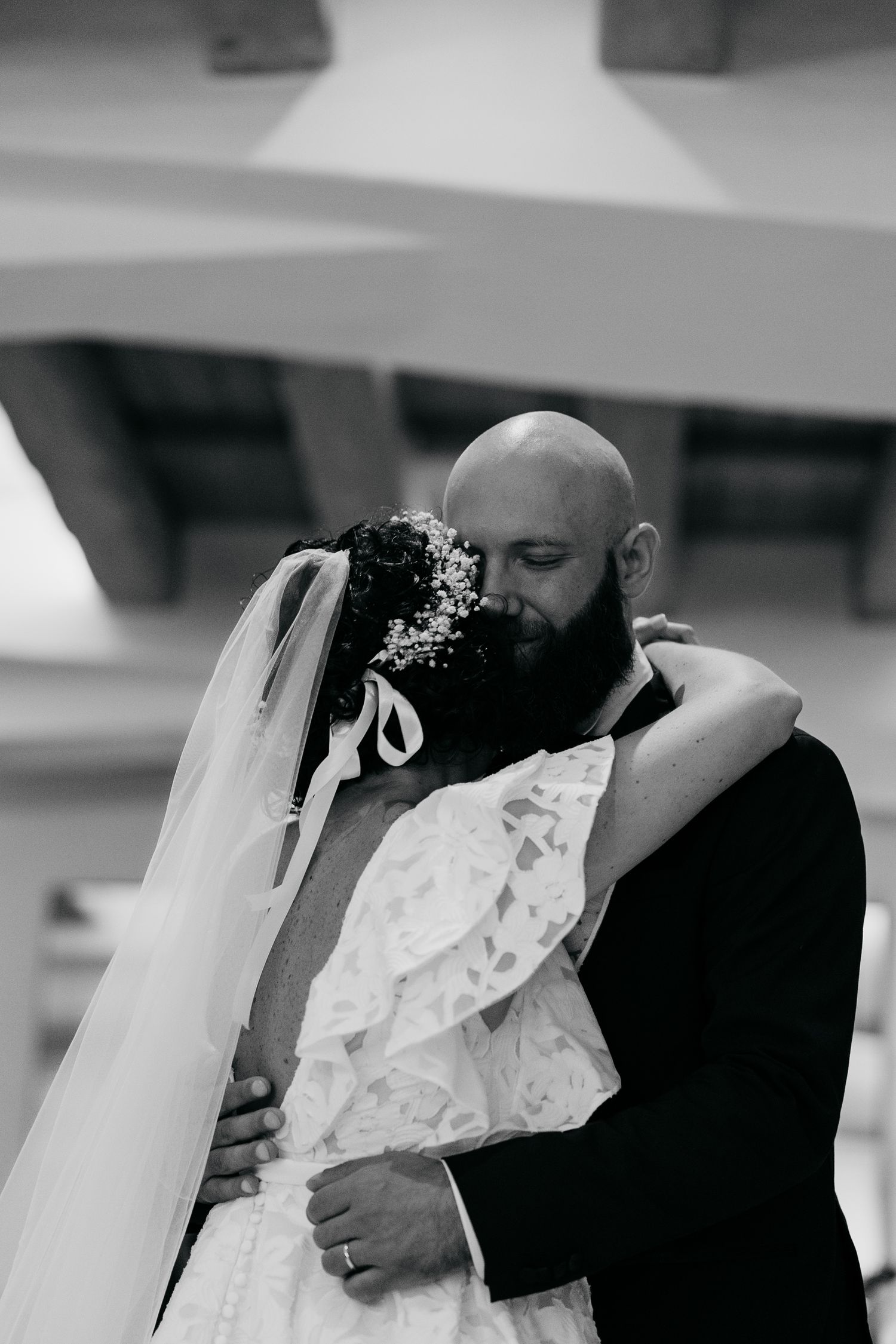 Intimate black and white wedding portrait showing tender embrace and lace details.