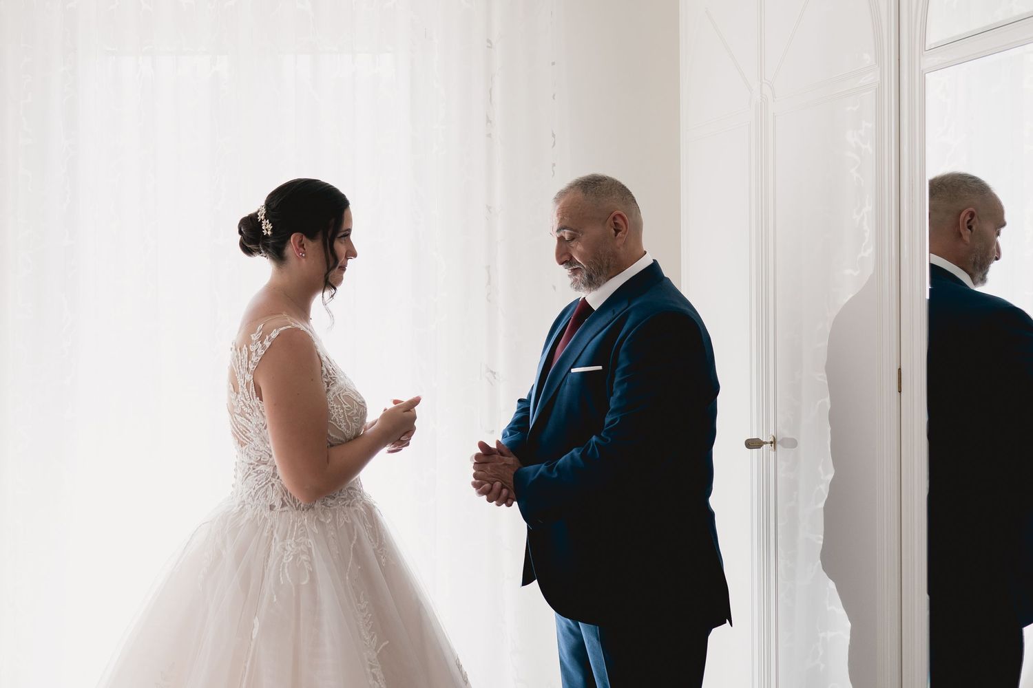 Wedding moment captured in bright natural light as two people share a conversation indoors.