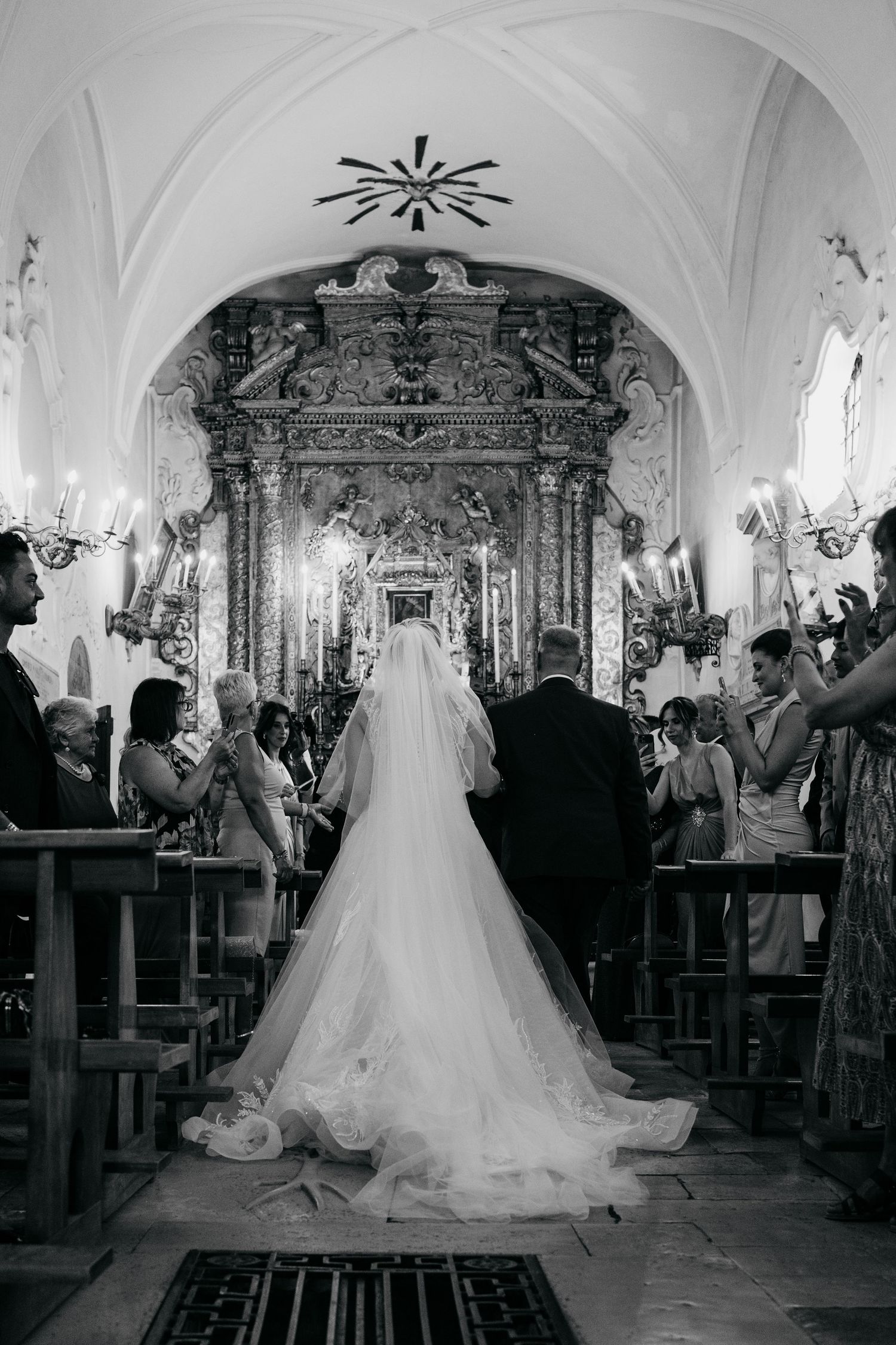 A bride in a flowing white gown stands at the altar of an ornate church with vaulted ceilings and baroque decor.