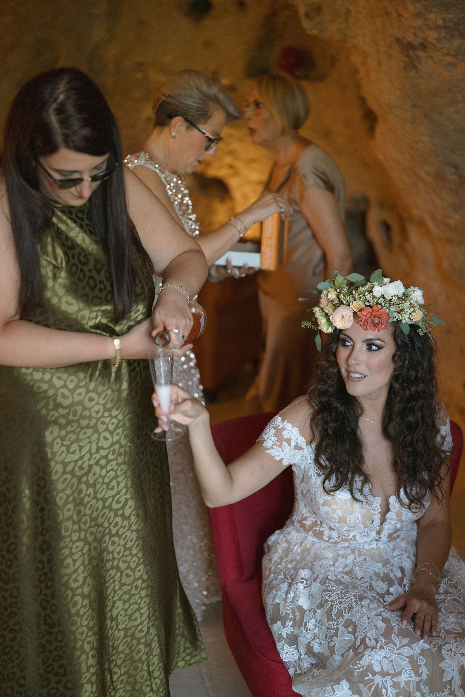 Two people share an intimate moment during a wedding, with one wearing a green dress and the other in white lace.