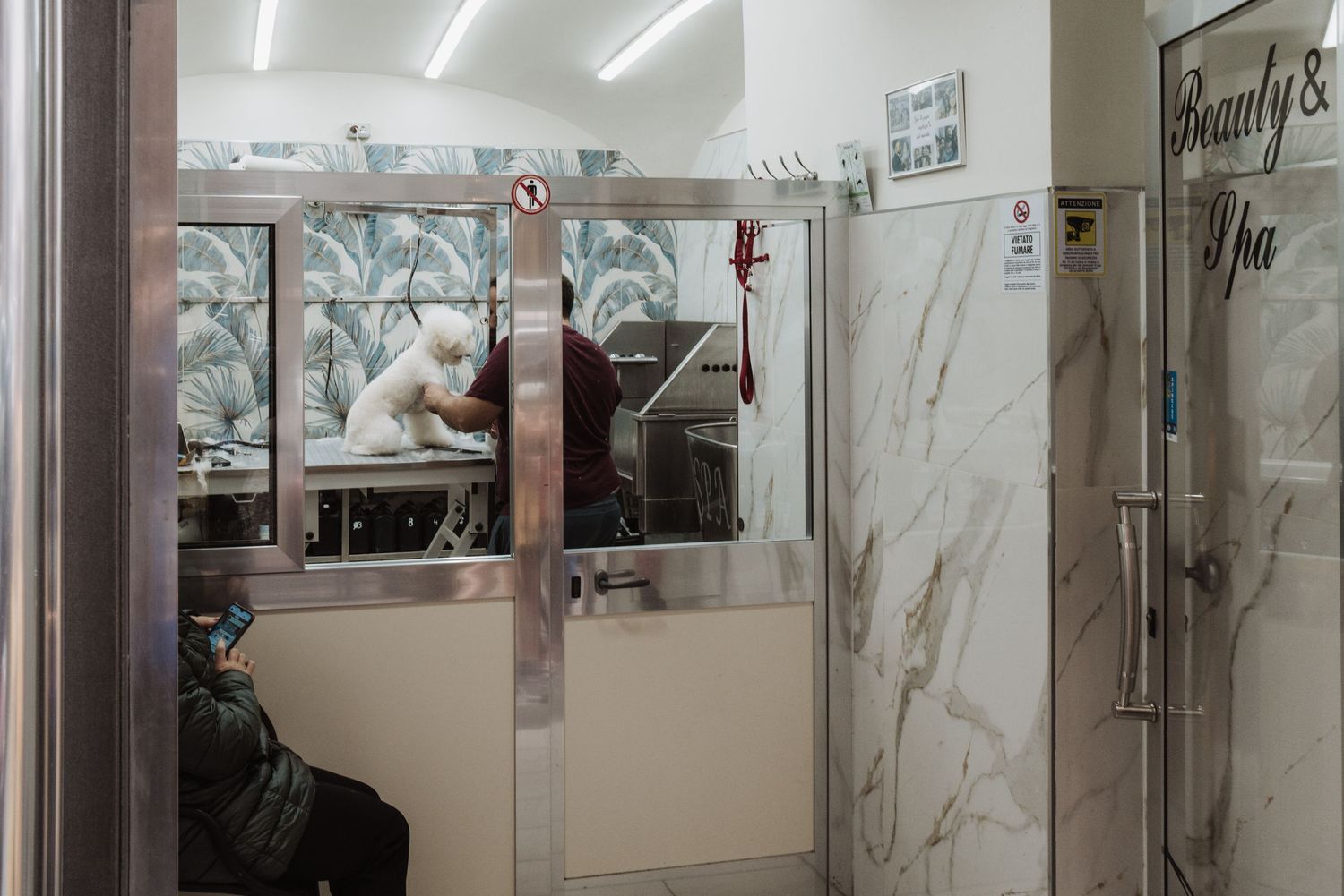 Interior view of a modern salon workspace with marble-style walls and bright fluorescent lighting visible through glass doors.