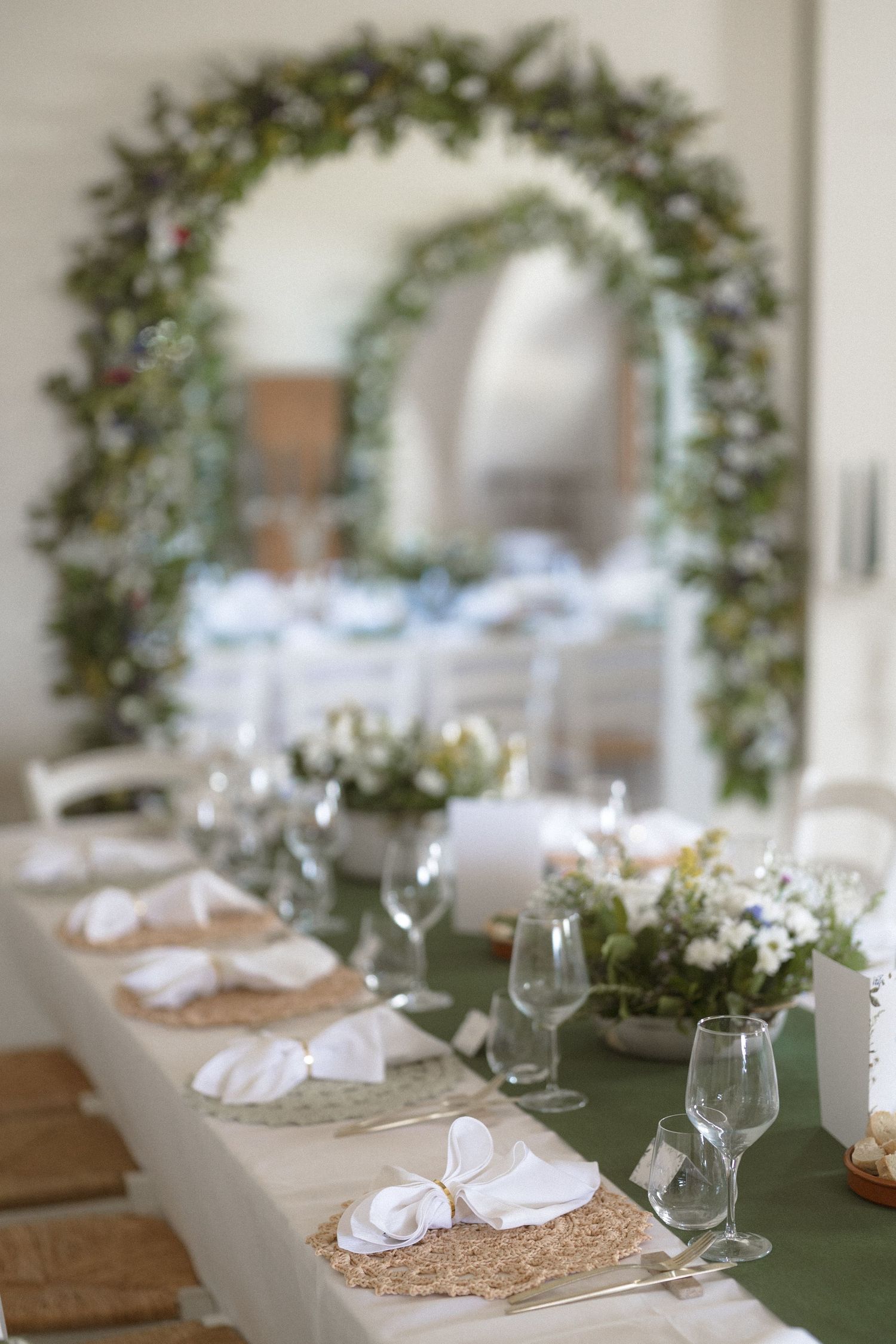 Elegant wedding reception table settings with green foliage wreaths and rustic place settings.