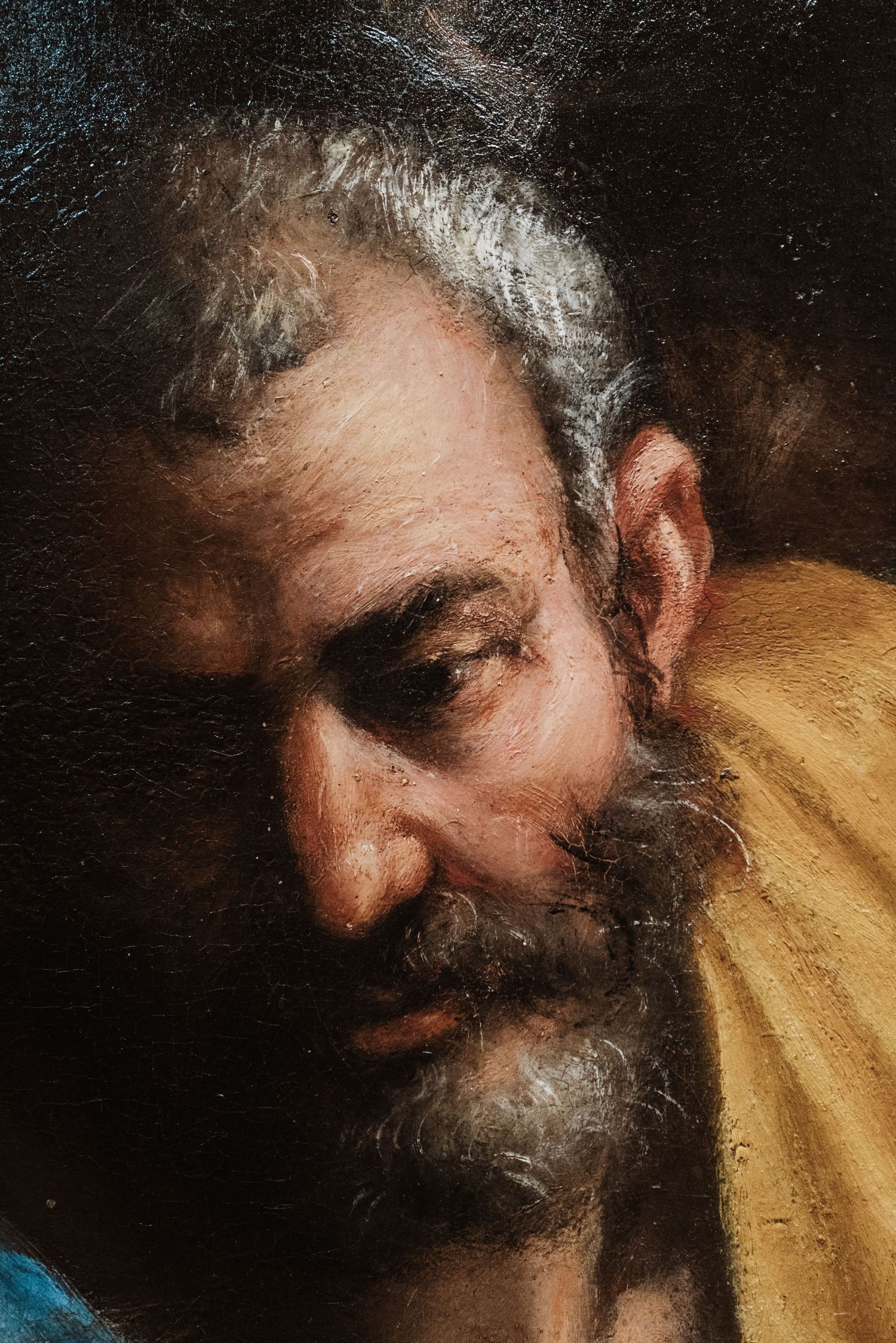 Close-up detail of an oil painting showing aged man with gray beard and weathered features.