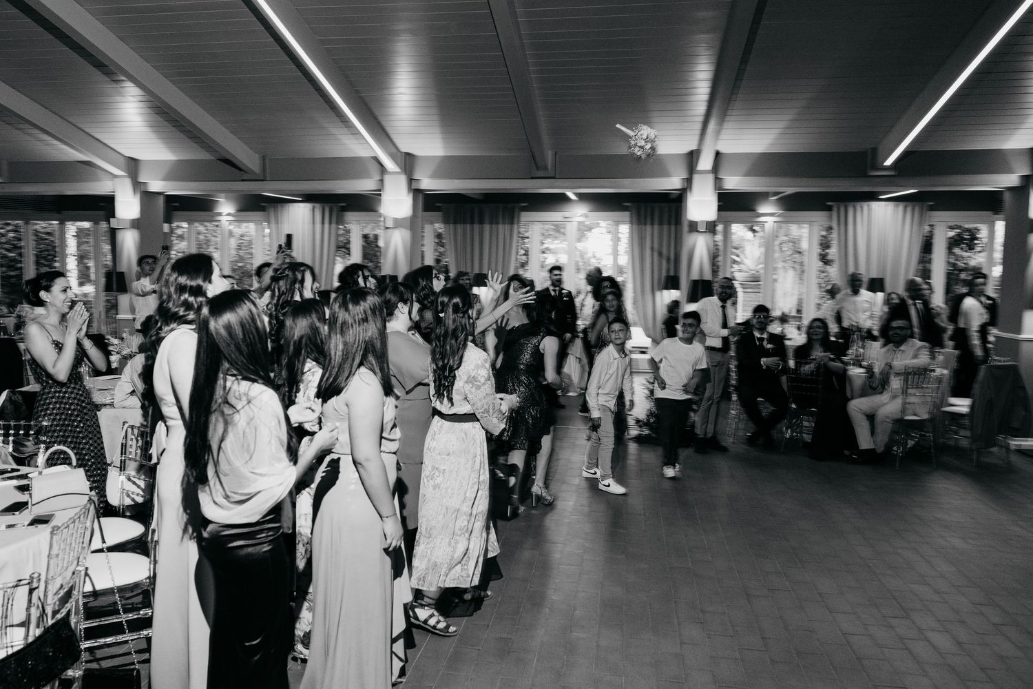 Black and white panoramic view of a wedding reception with guests filling the dance floor.
