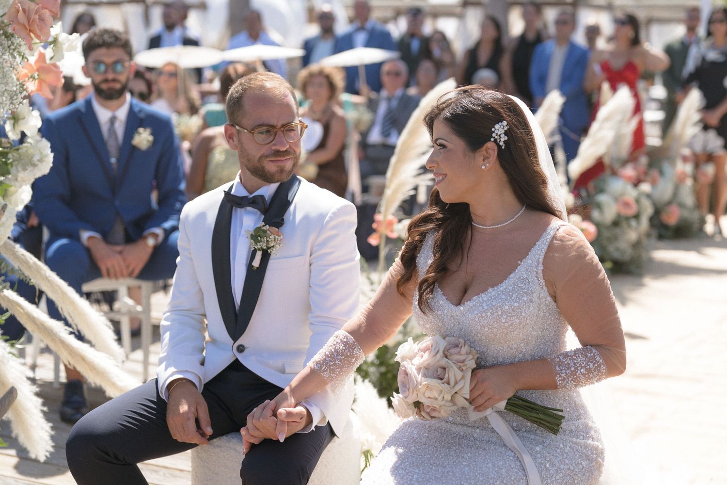 Outdoor wedding celebration with guests gathered in a sunny garden setting.