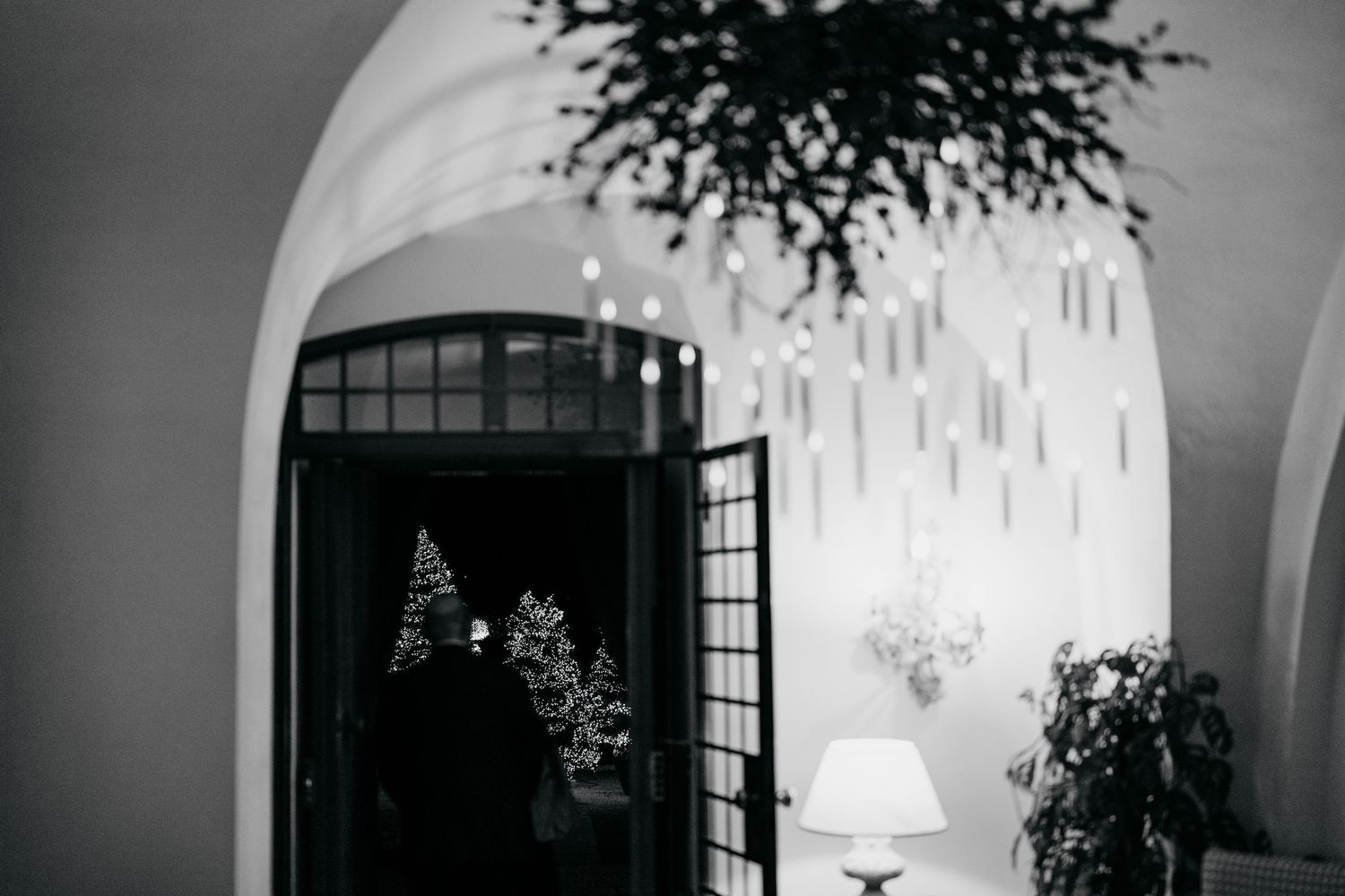 Black and white photo of an elegant venue entrance with arched doorway and decorative chandelier.