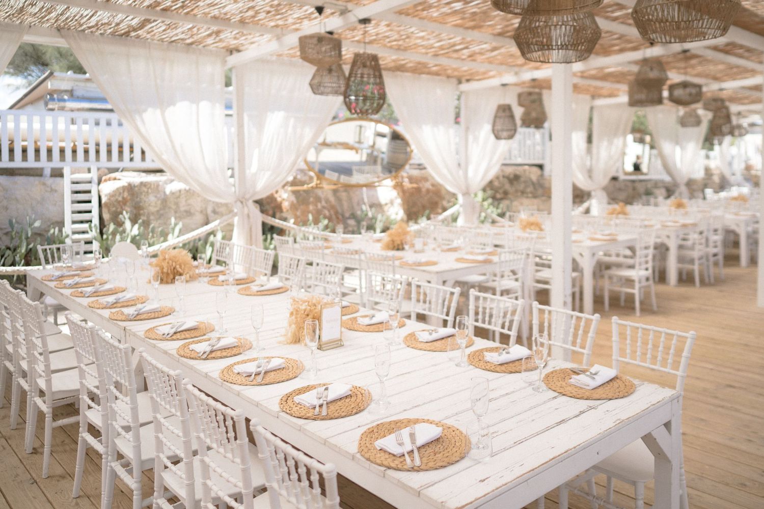 Elegant wedding reception venue with white decor, chandeliers, and place settings.