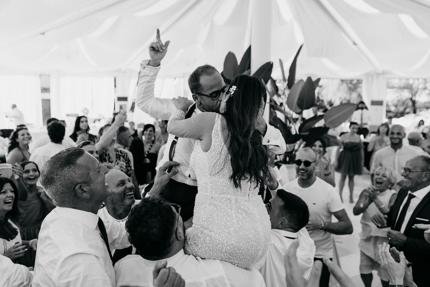 Black and white photos of wedding guests celebrating under a reception tent.