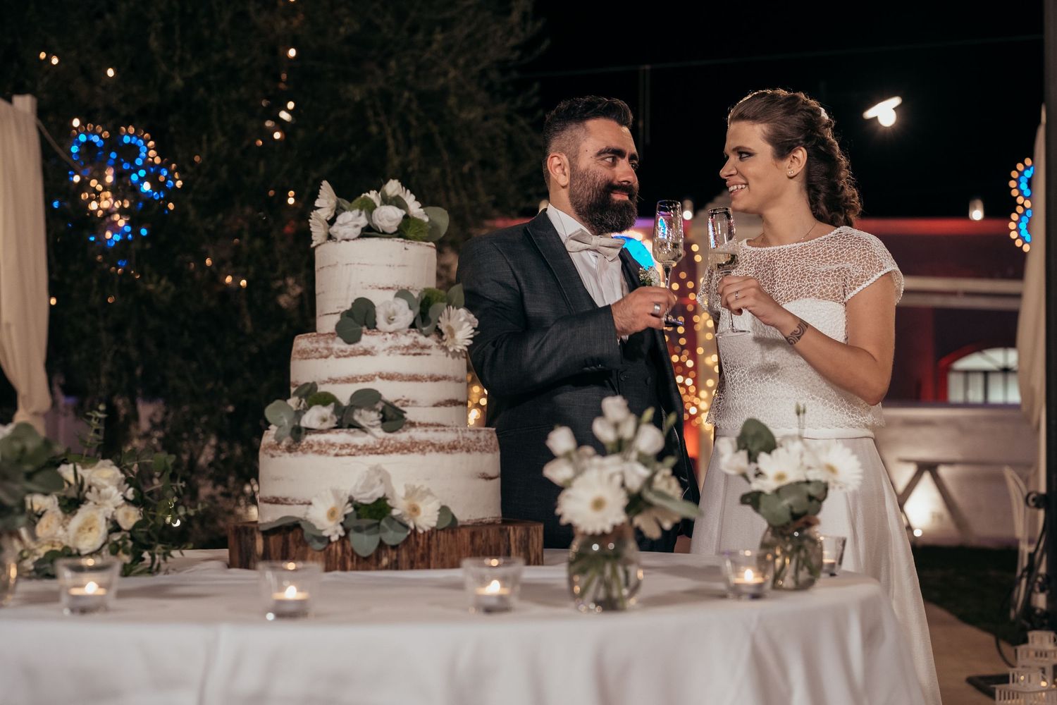 Couple sharing a toast beside their beautiful floral-decorated wedding cake.