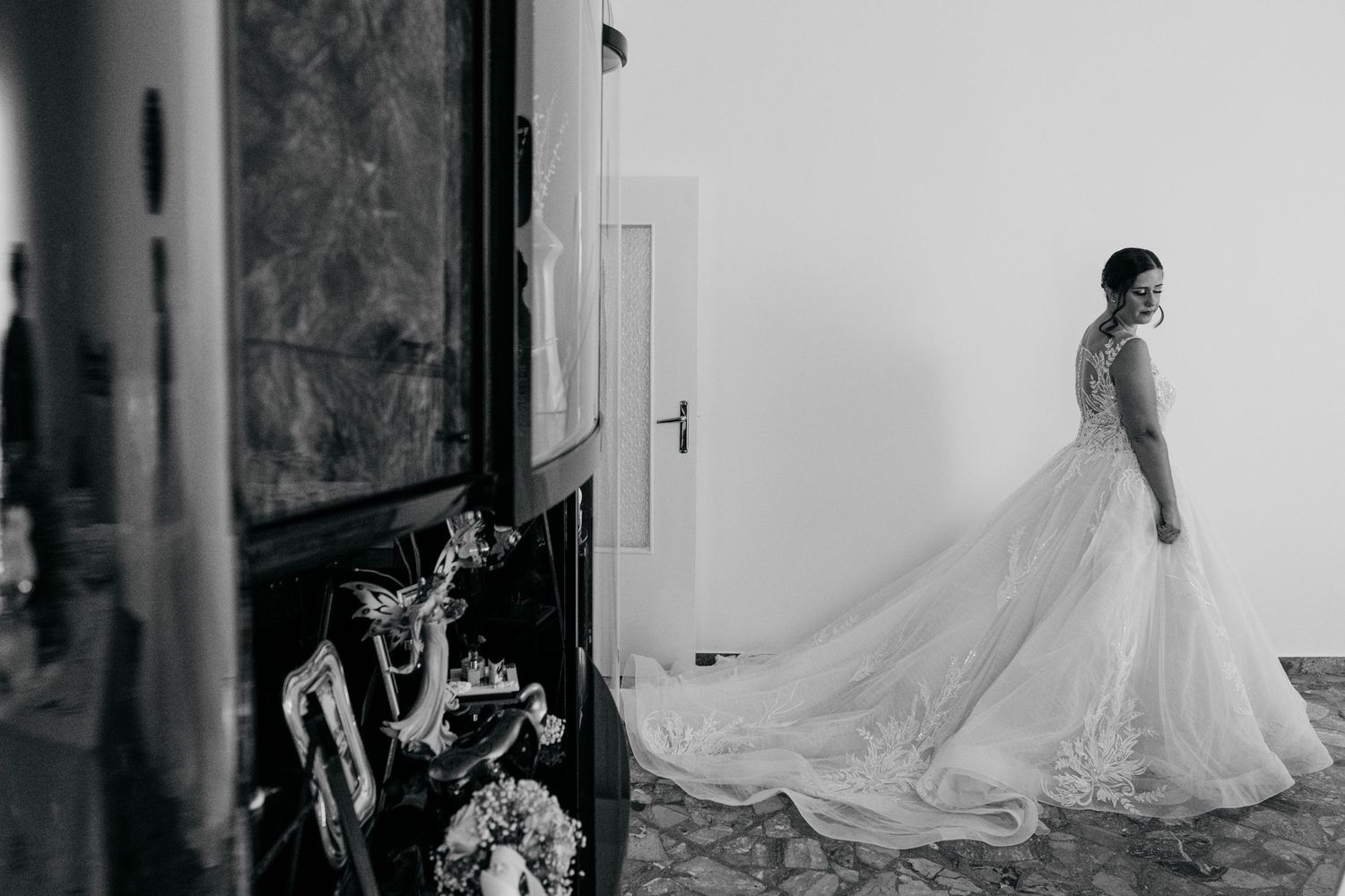 Black and white artistic portrait of a bride in a flowing wedding gown with dramatic lighting.