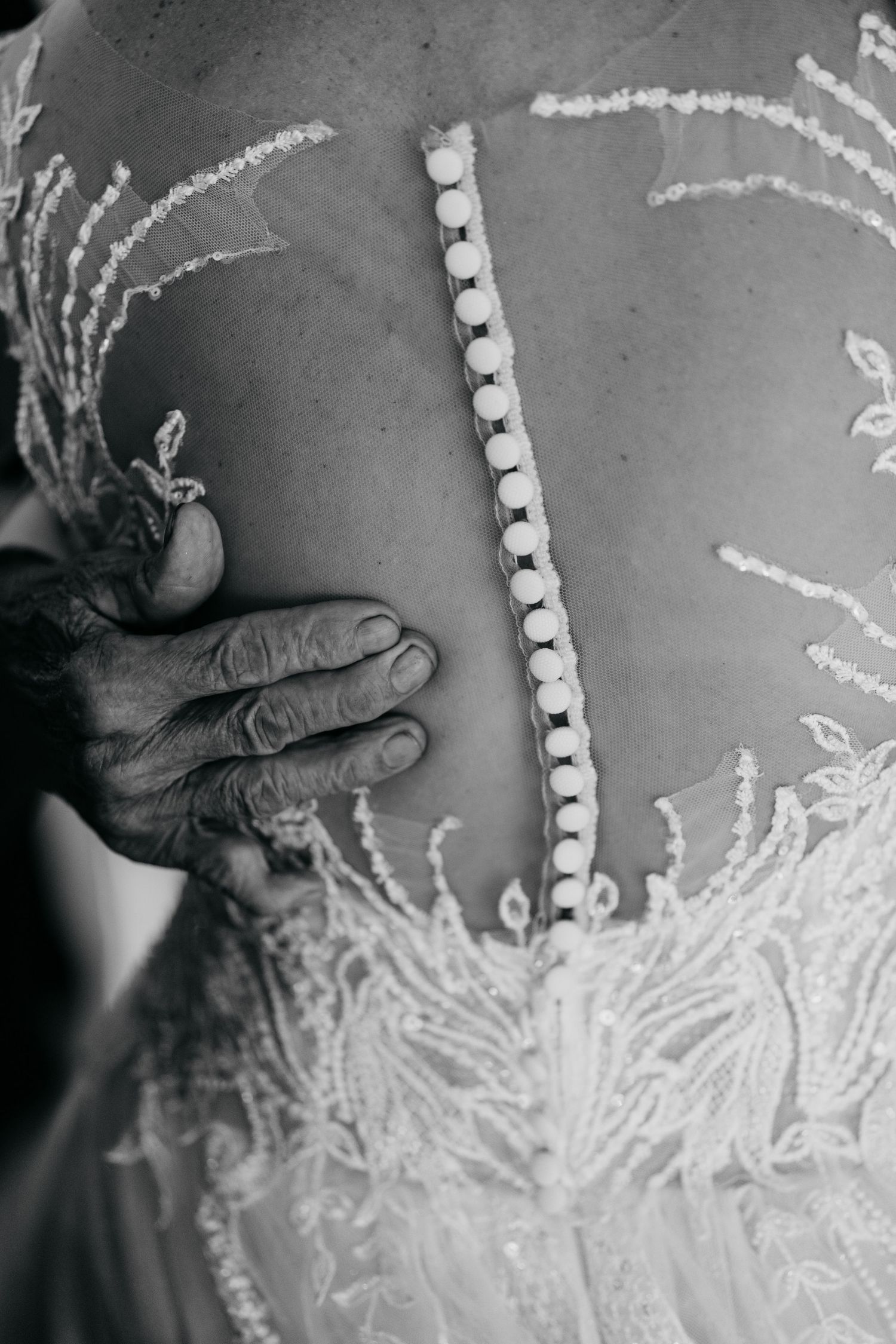 Close-up detail of intricate beading and buttons on the back of a wedding dress.