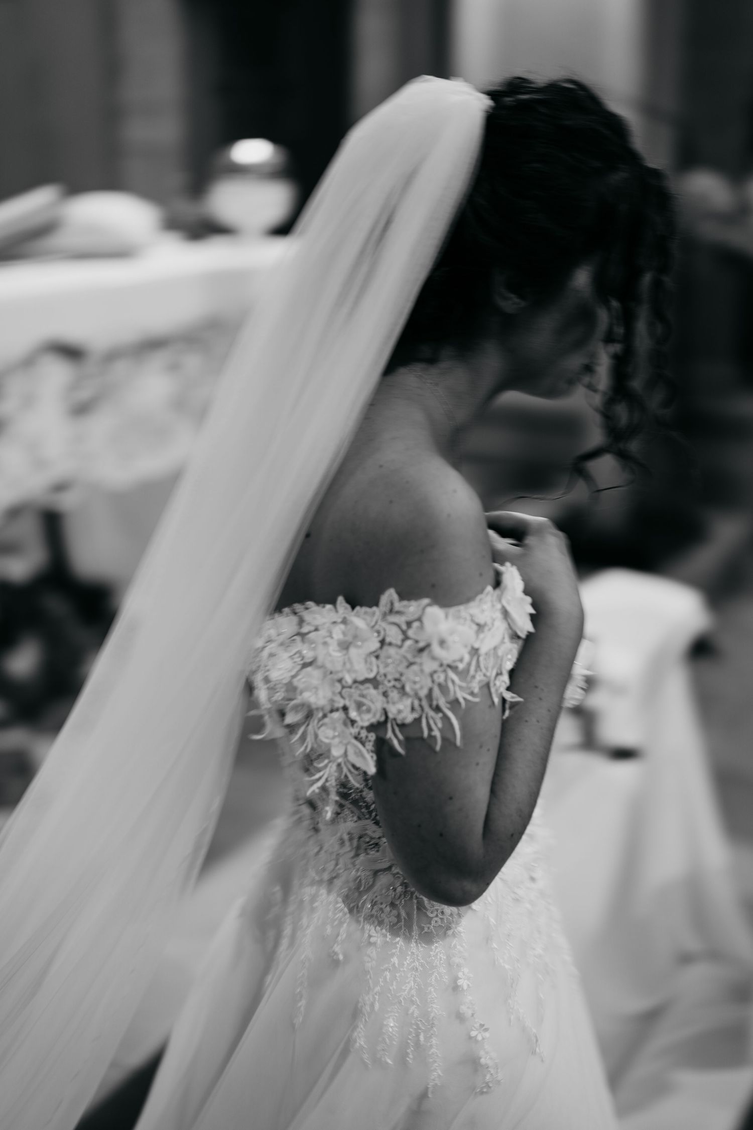 A detailed back view of a bride's wedding dress showing delicate lace appliques and long flowing veil.