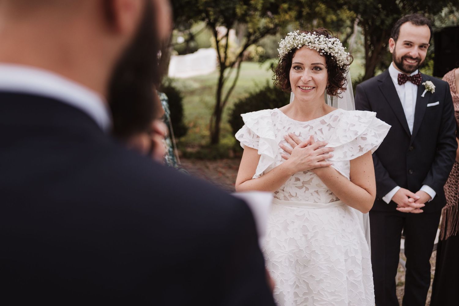 Emotional wedding ceremony moment with delicate lace dress and floral crown details.