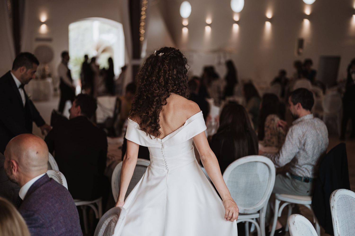 An elegant wedding reception in a dimly lit venue with white decor and chairs.
