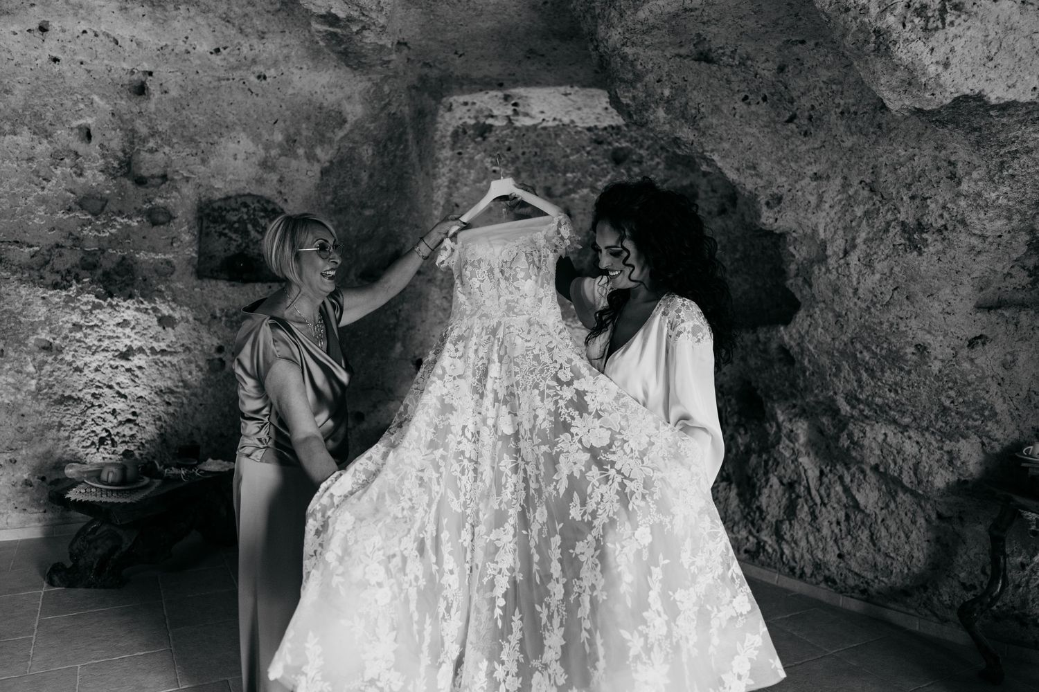 Intimate black and white photography against textured stone wall.