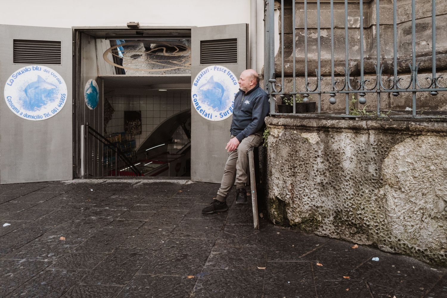 Person leans against wall next to entrance with circular blue and white signs.
