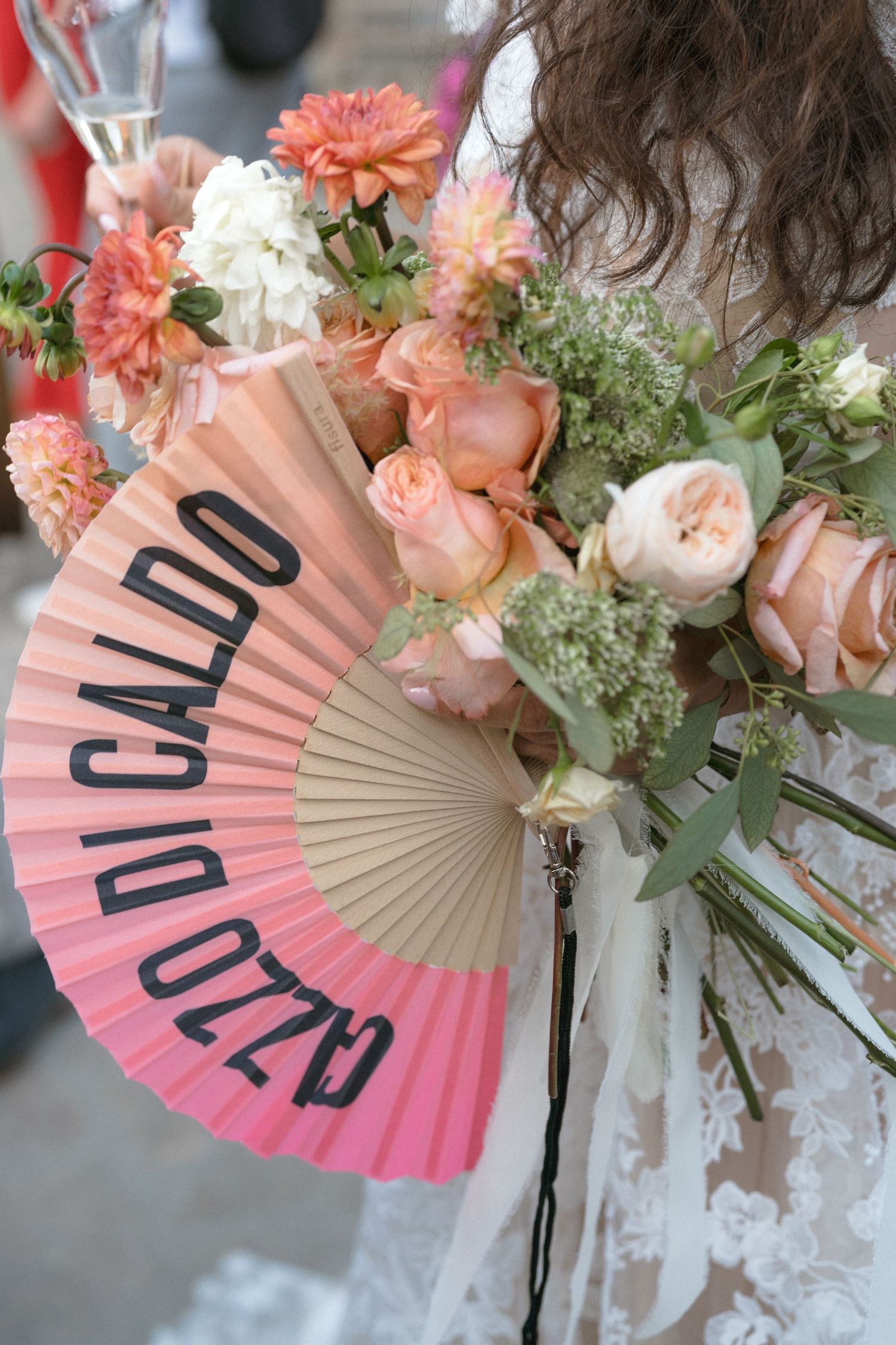 Coral and peach floral arrangements with decorative fans create an elegant wedding display.