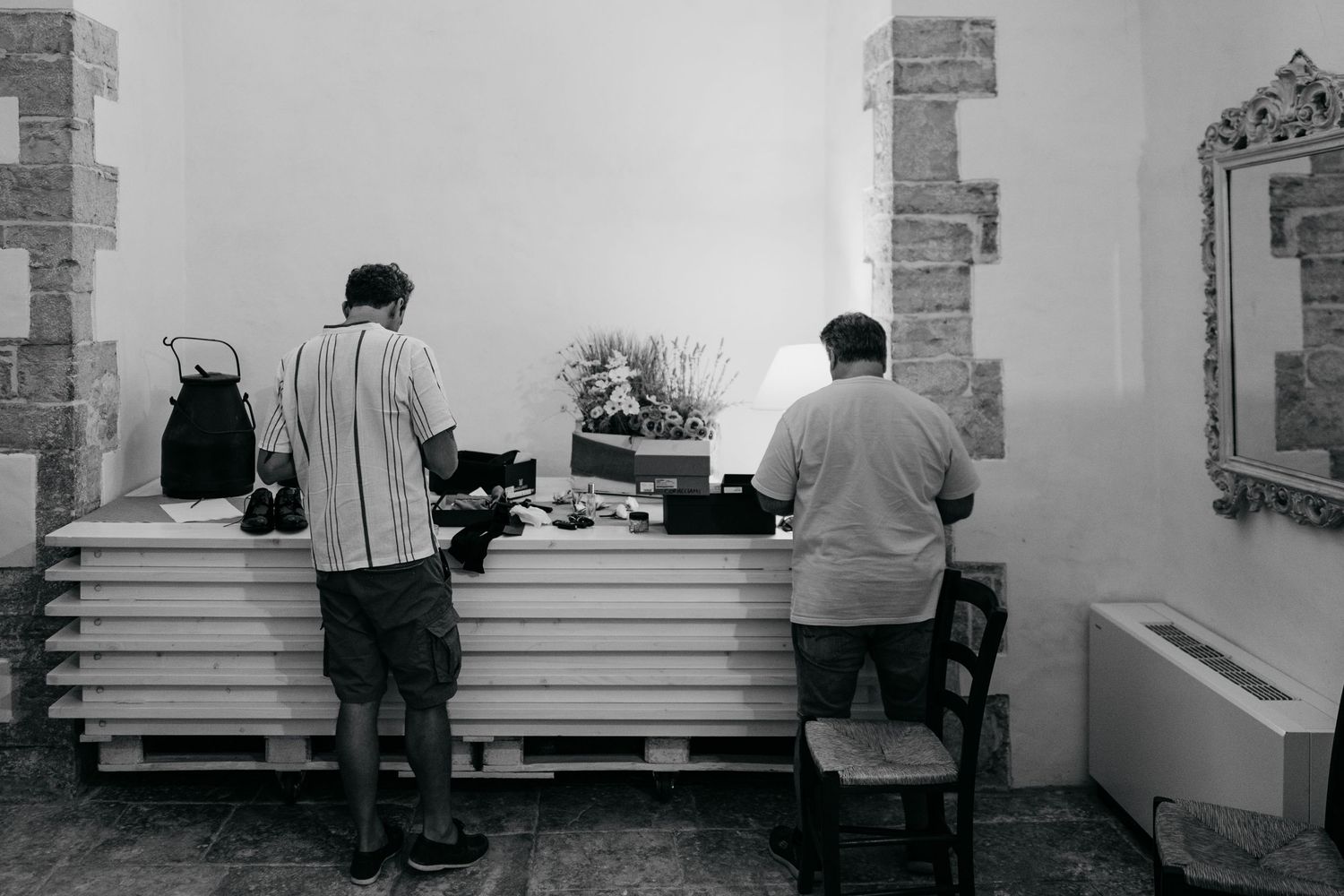 Two people working at a preparation station in black and white photography.