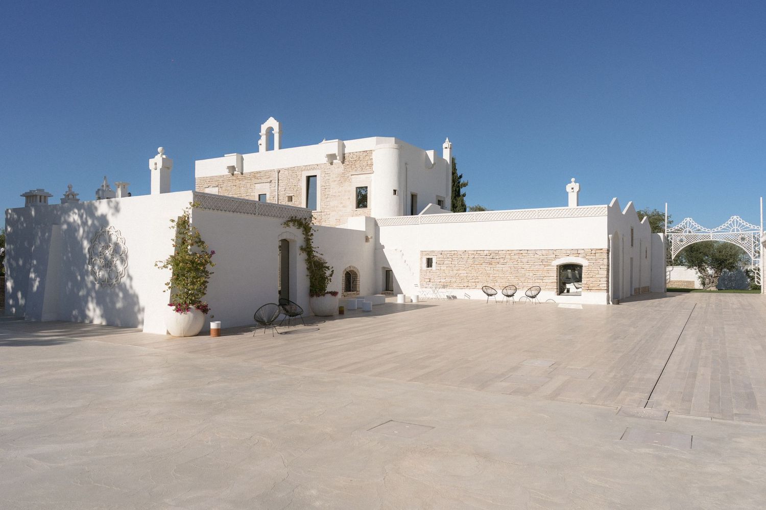 Stunning whitewashed Mediterranean wedding venue with stone archway entrance and spacious courtyard under clear blue sky.