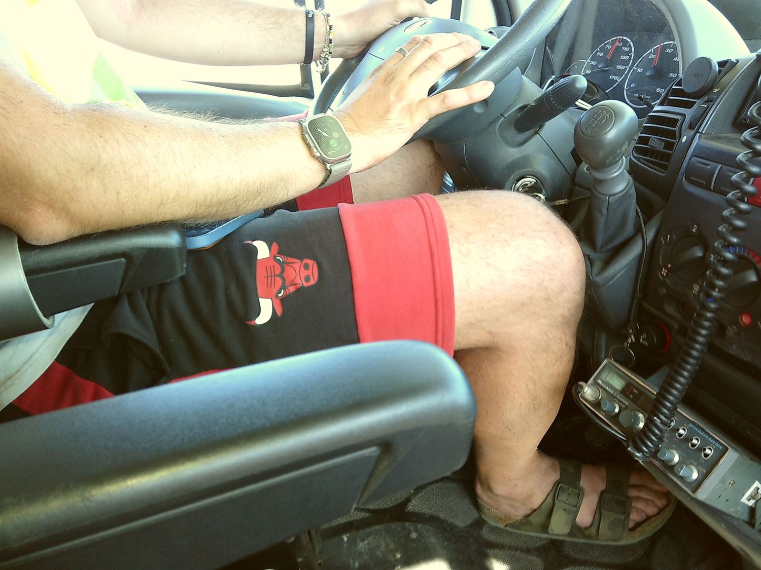Interior view of driver's seat showing shorts-clad leg and vehicle controls.
