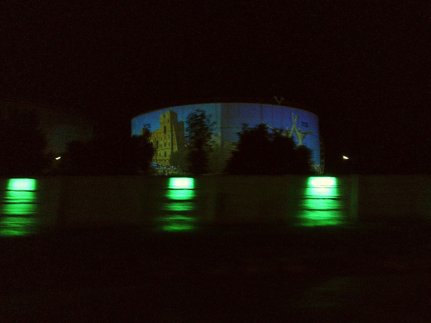 Dark structure with green lights illuminating its base at night.
