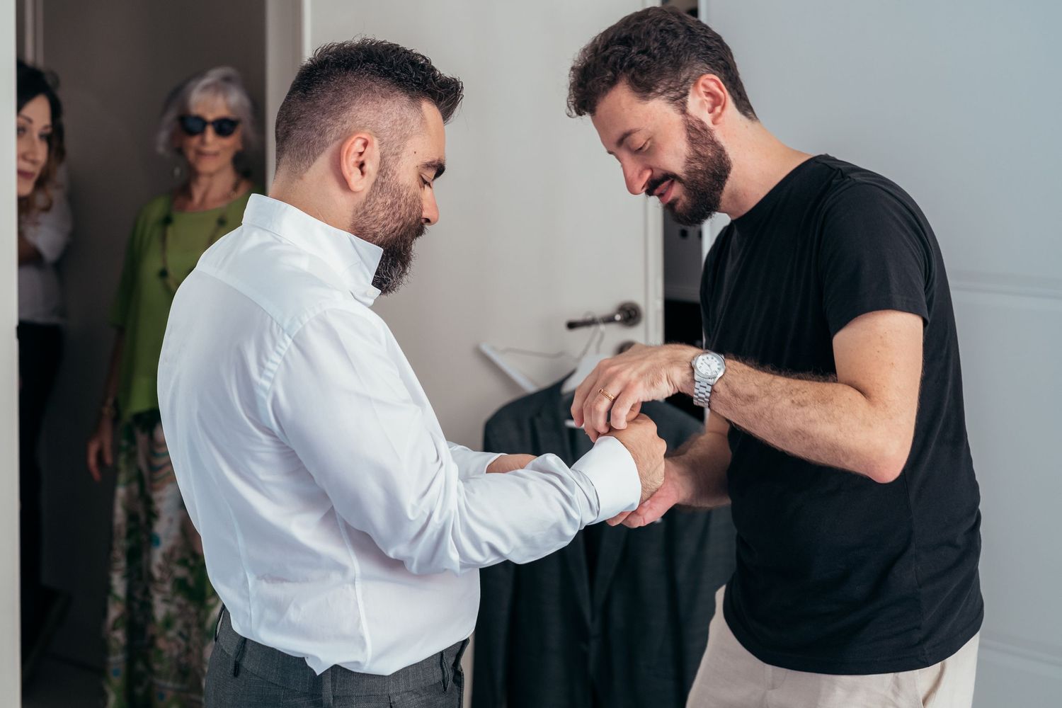 People assisting with formal dress preparations indoors.