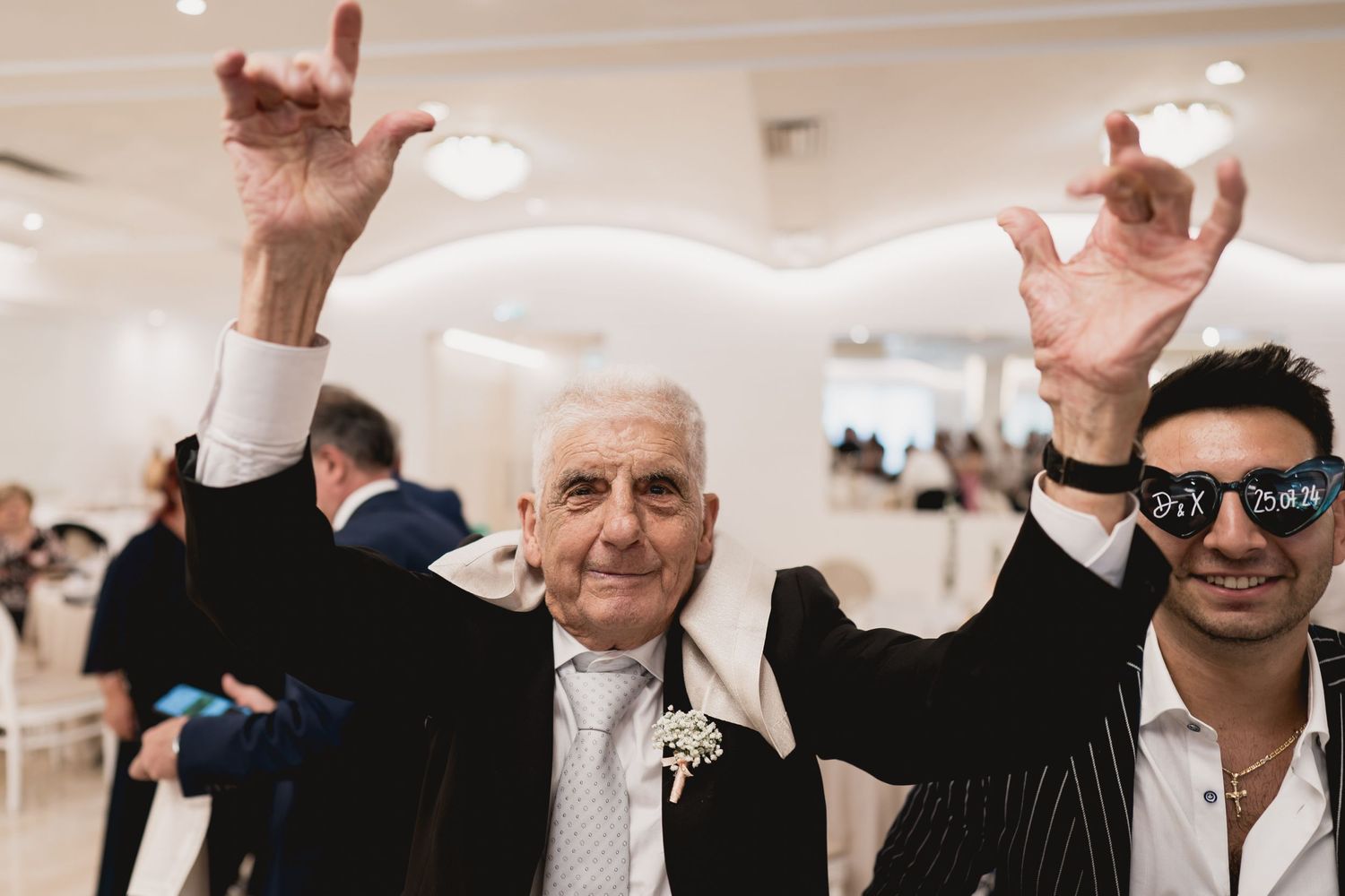 Wedding guests celebrating enthusiastically on the dance floor during reception festivities.