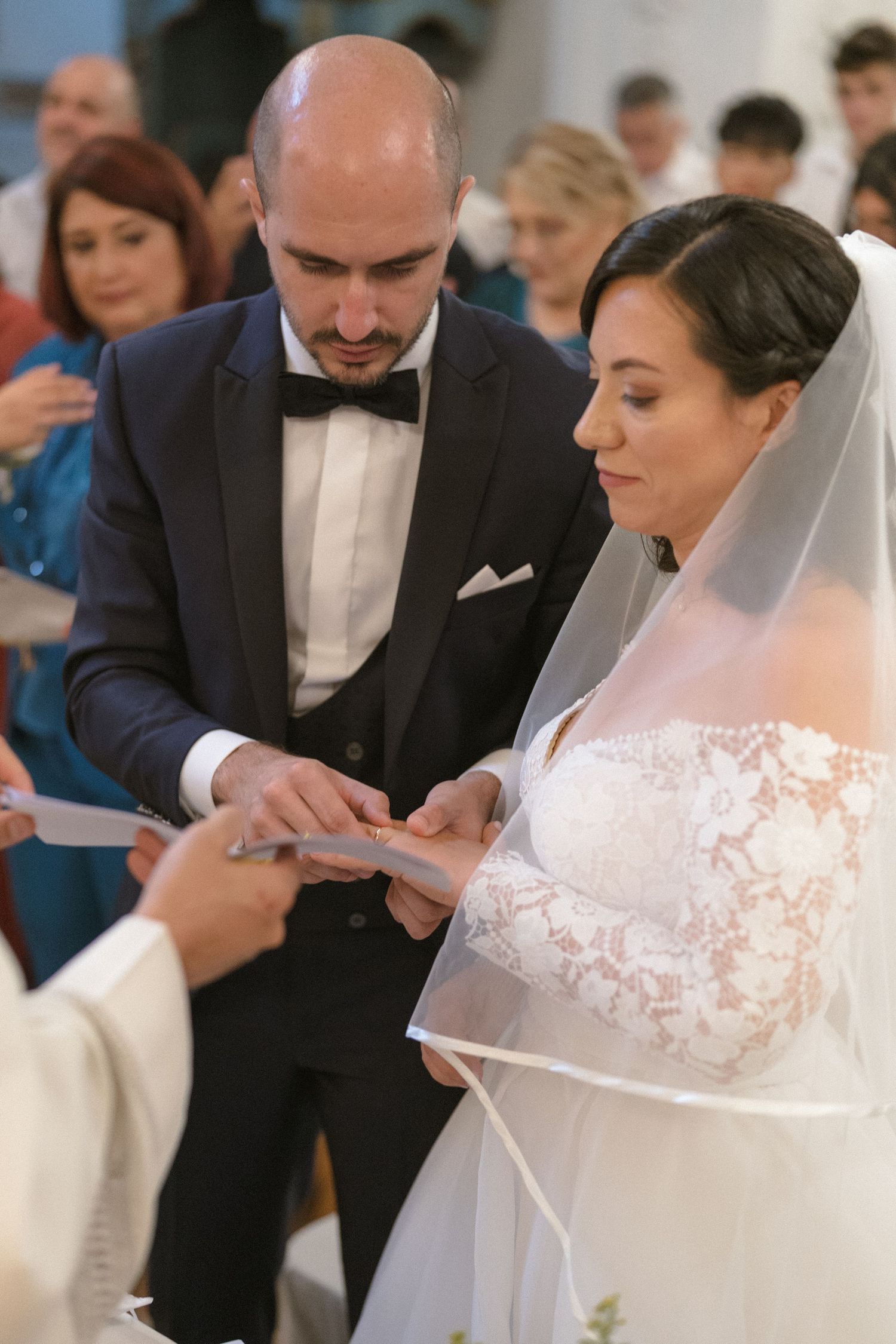 Couple in formal wedding attire reads from papers during church ceremony.