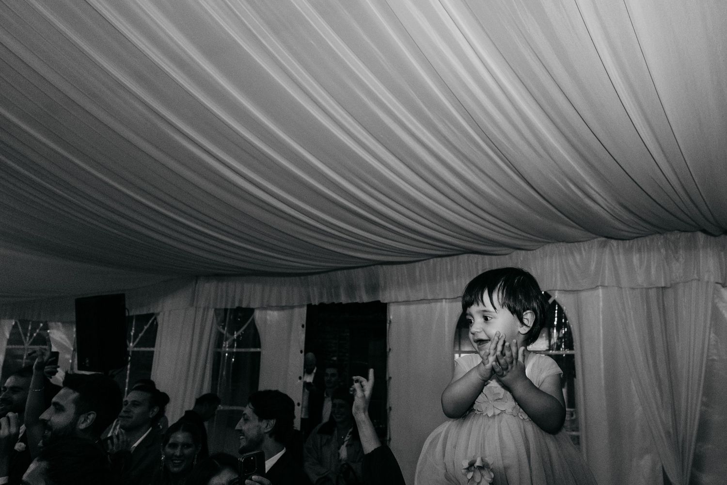 Interior of an elegant white tent with draped fabric ceiling at a wedding reception.