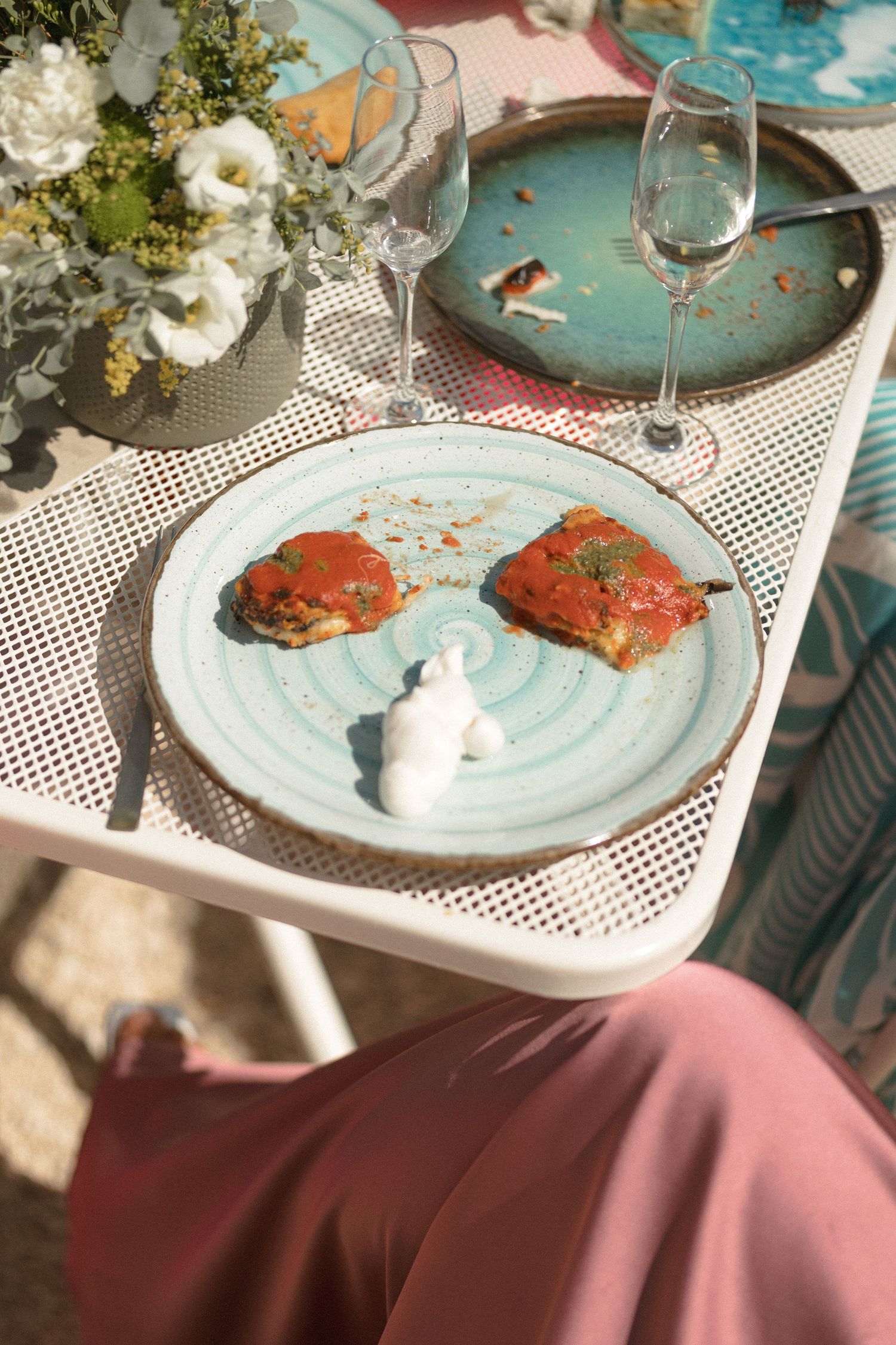 Elegant place settings with turquoise plates and seafood dishes on a white mesh table.