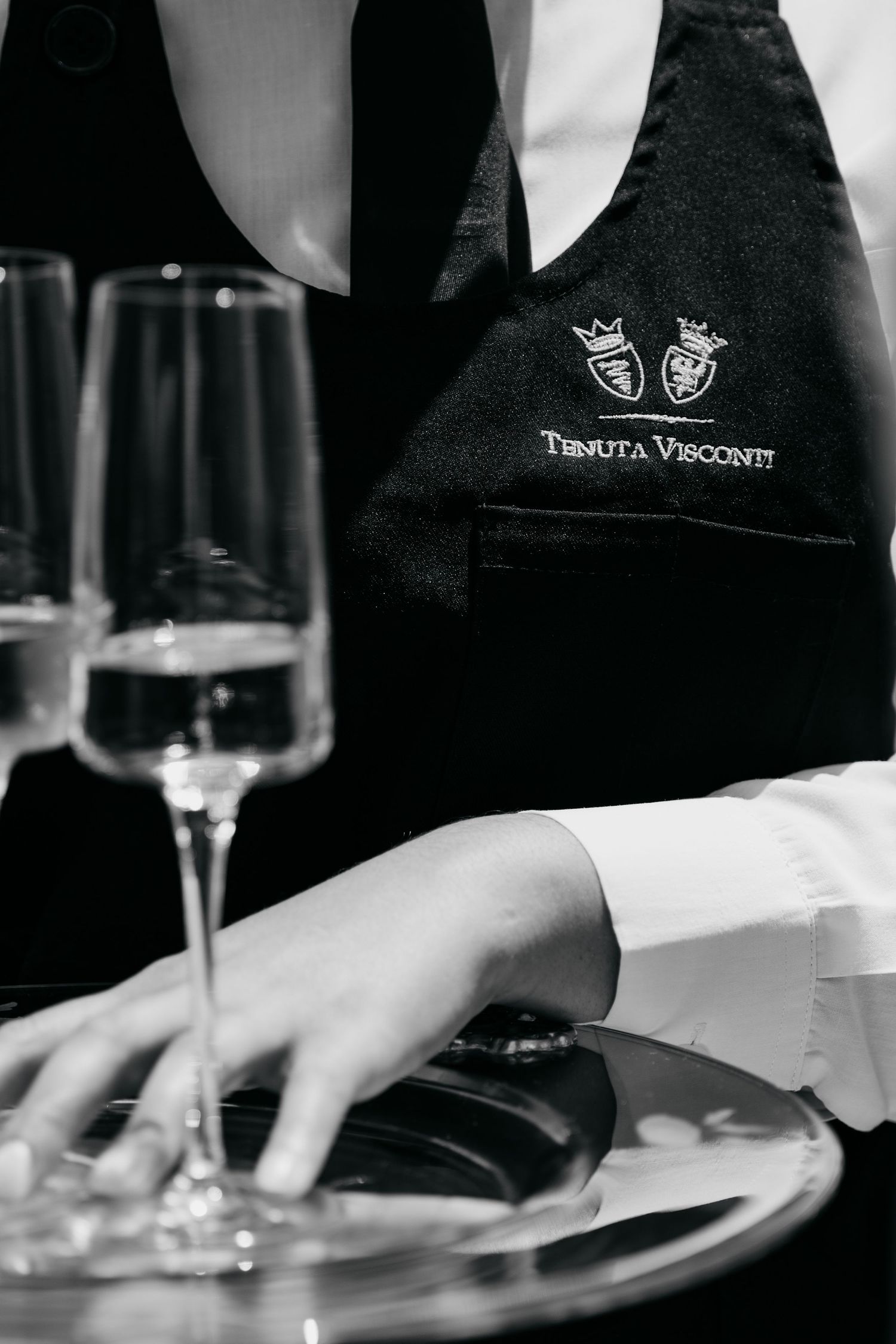 Professional waiter serving plated dishes at an upscale restaurant with elegant table settings.