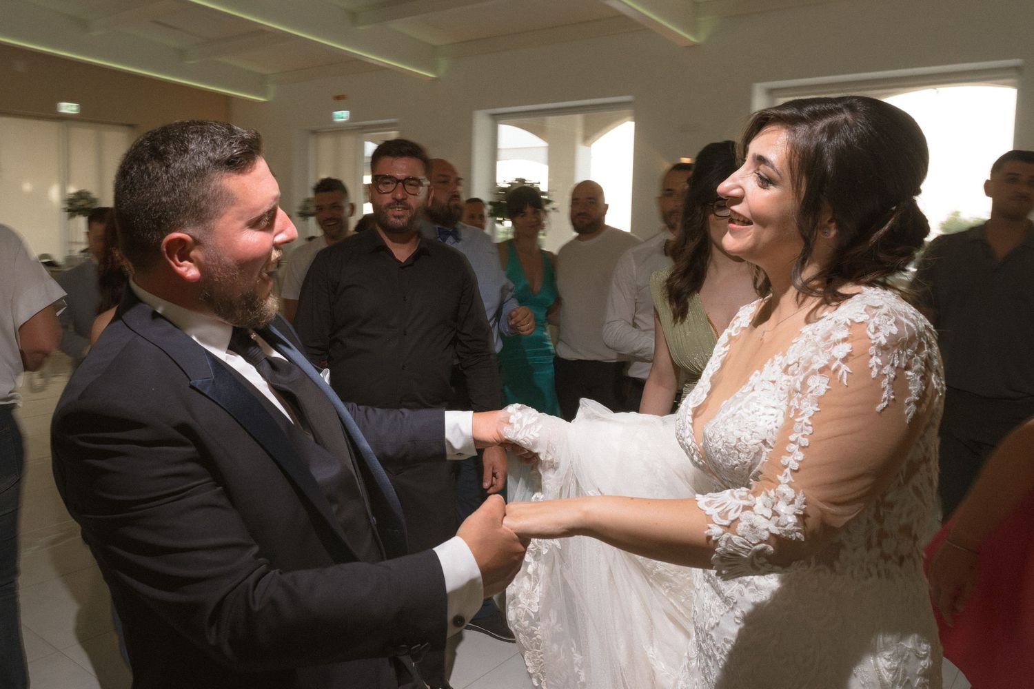 A couple shares a joyful moment during their wedding ceremony indoors surrounded by guests.