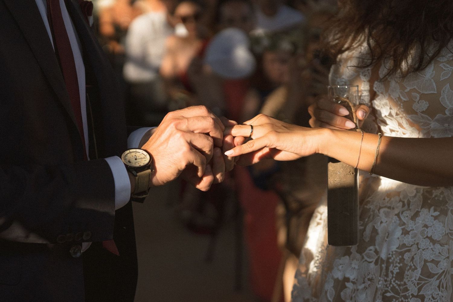 Close-up of hands exchanging wedding rings during ceremony in soft natural light.