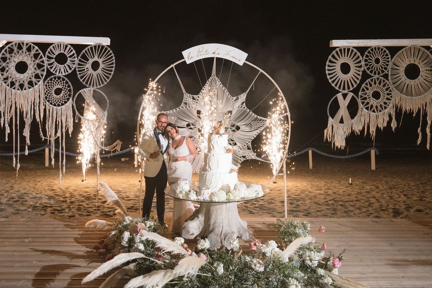Wedding reception setup with illuminated macrame hangings and bohemian decor at night.