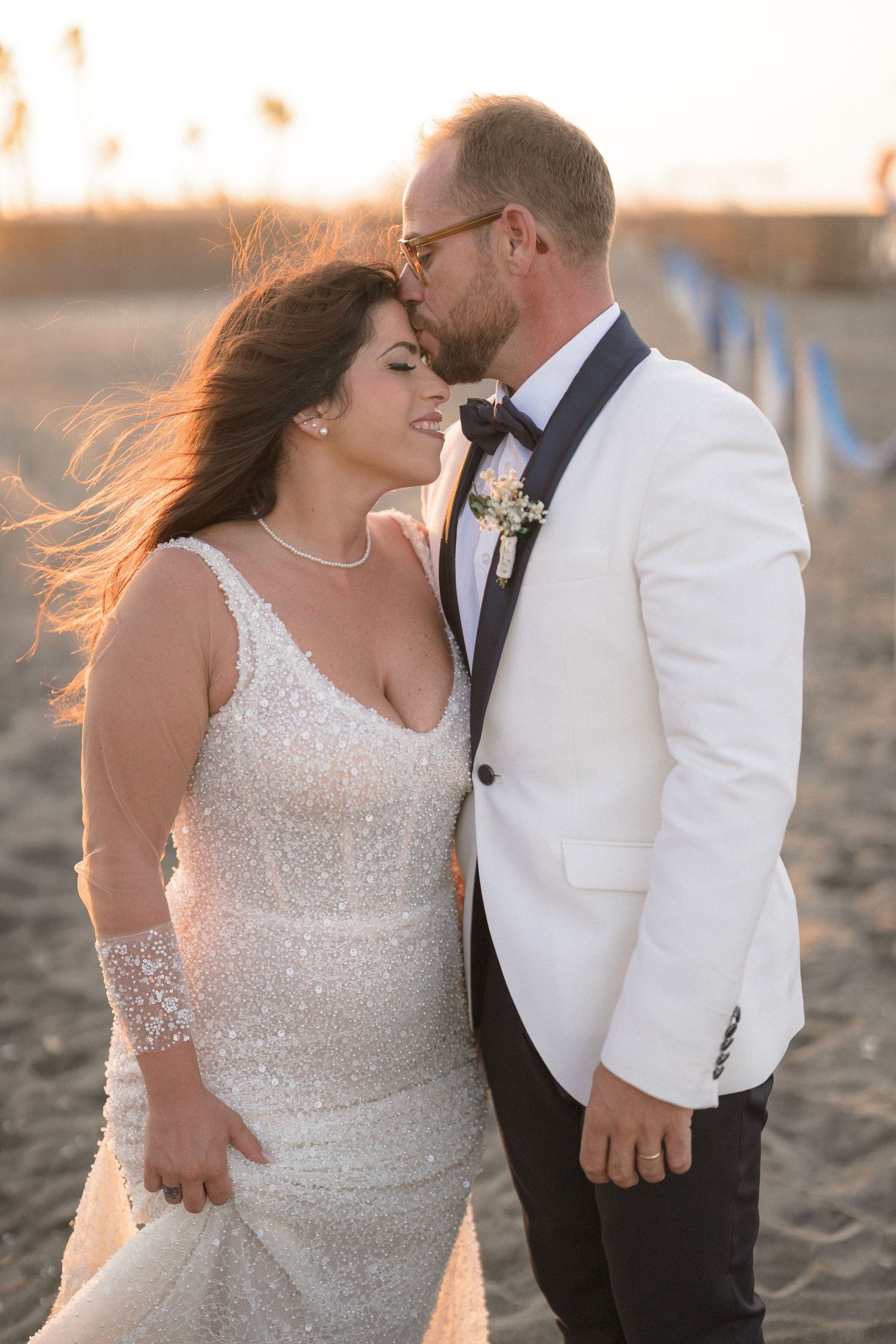 Romantic sunset beach portraits of newlyweds in white formal attire.