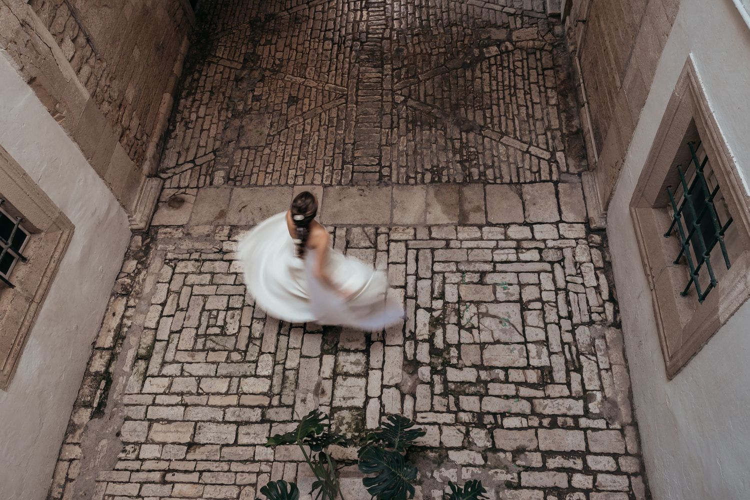 Overhead view of a bride in a white dress standing on an intricately patterned stone floor.