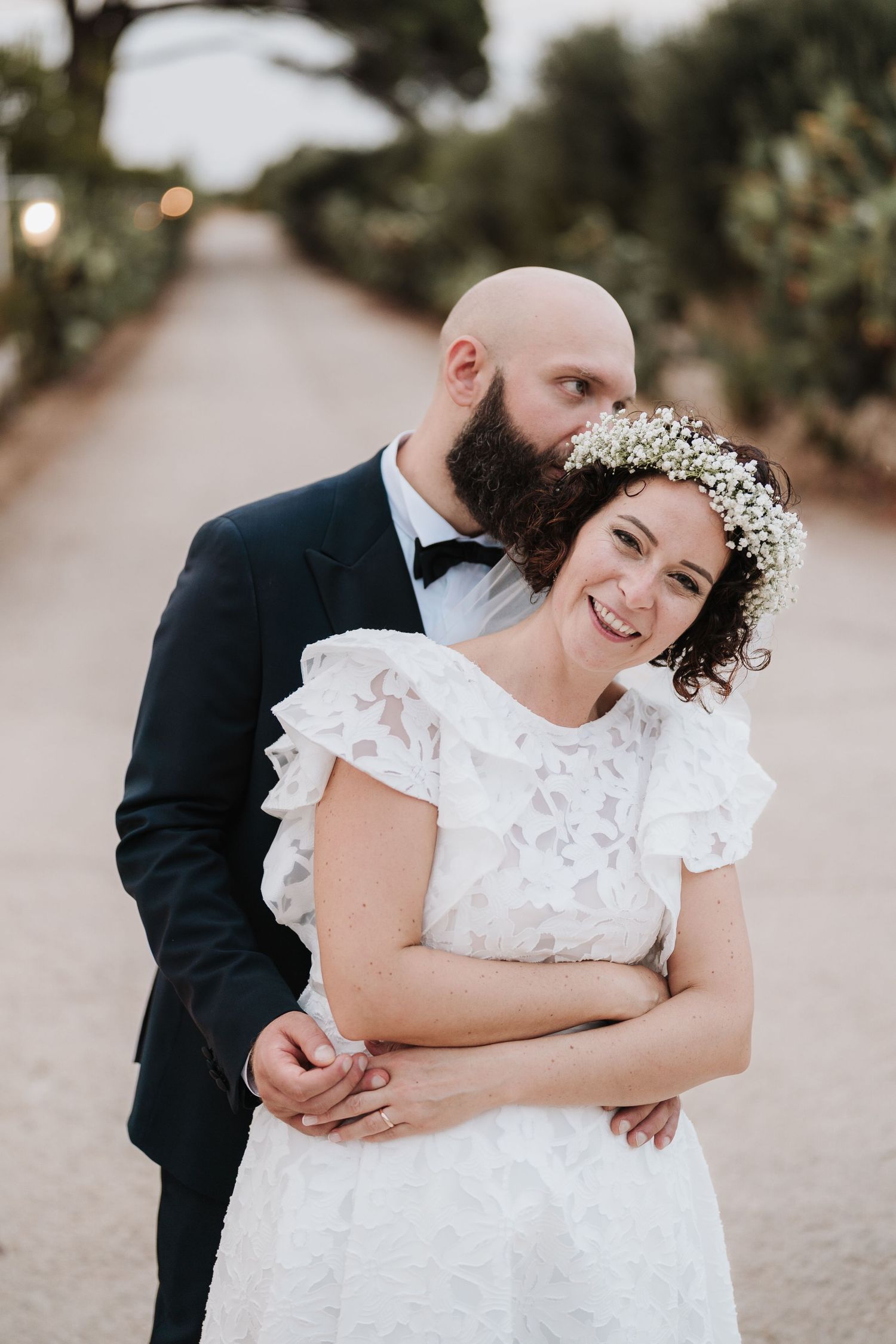 A romantic wedding portrait on a sunlit garden path.
