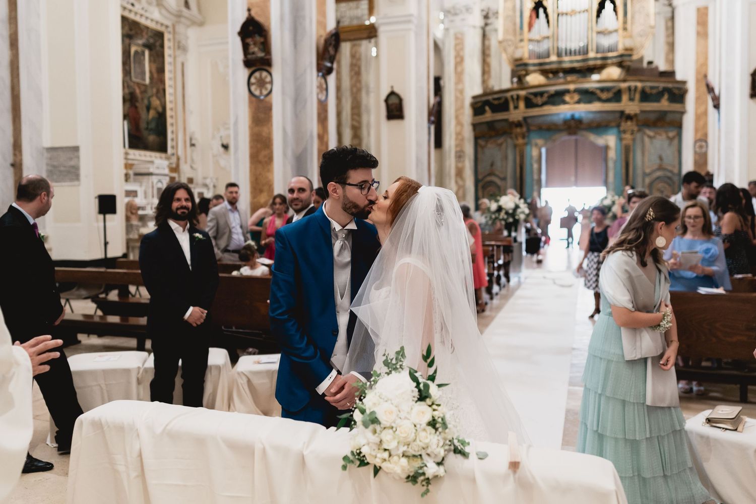 A romantic wedding ceremony in a grand historic church with white floral decorations and guests in formal attire.