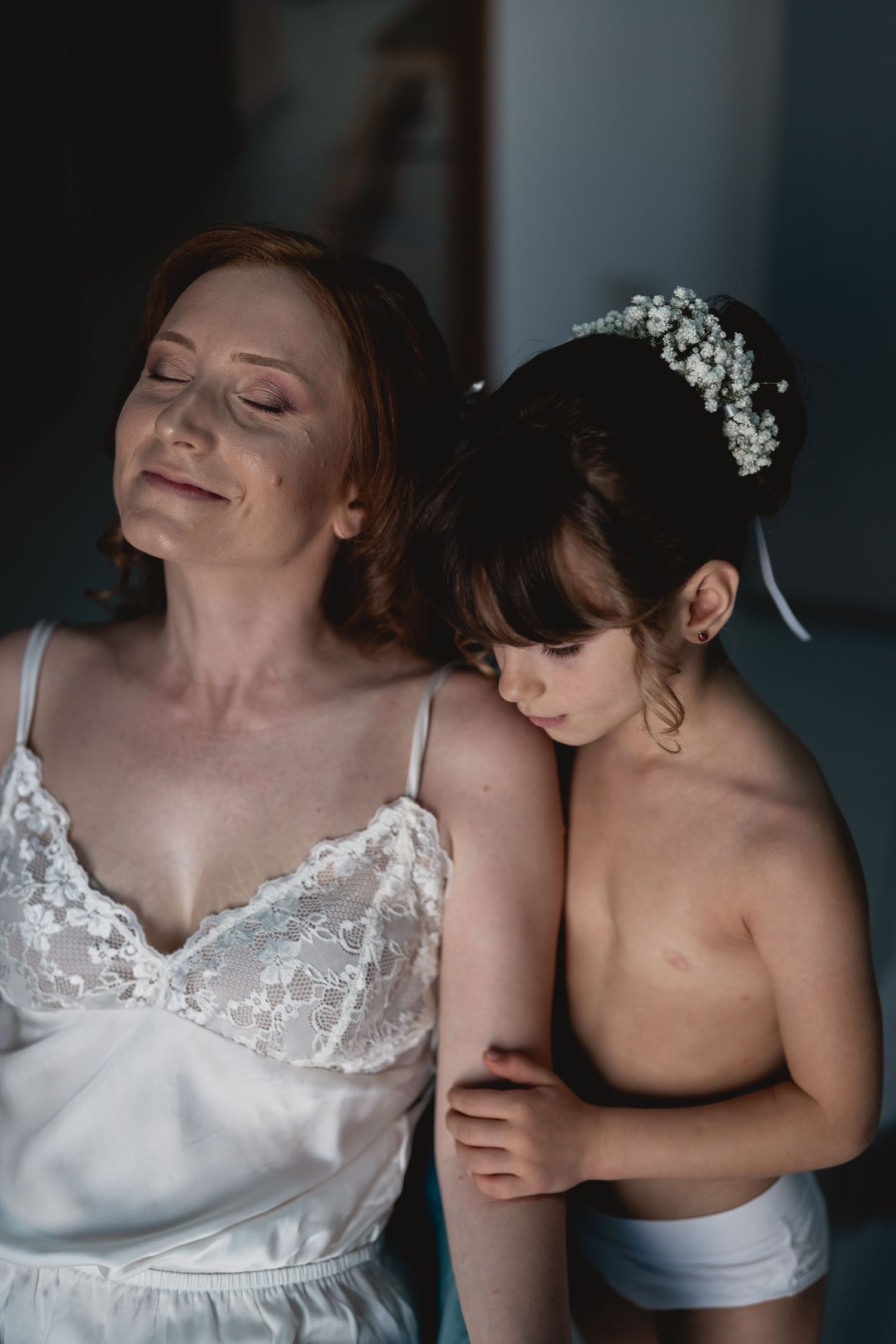 Intimate moment captured during wedding preparations showing elegant white lace details.