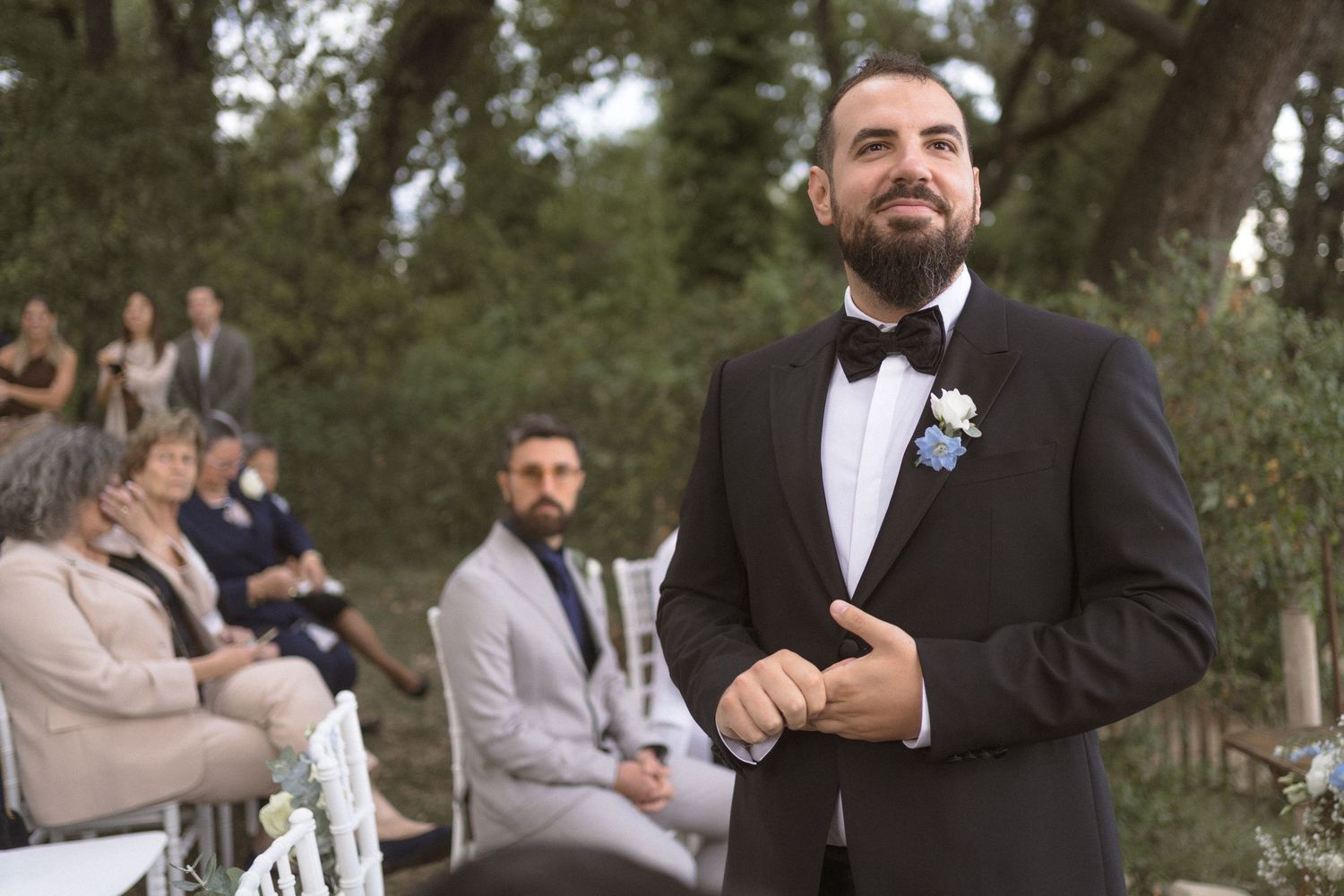 Wedding party members in formal attire gather outdoors under cloudy skies during a celebration.