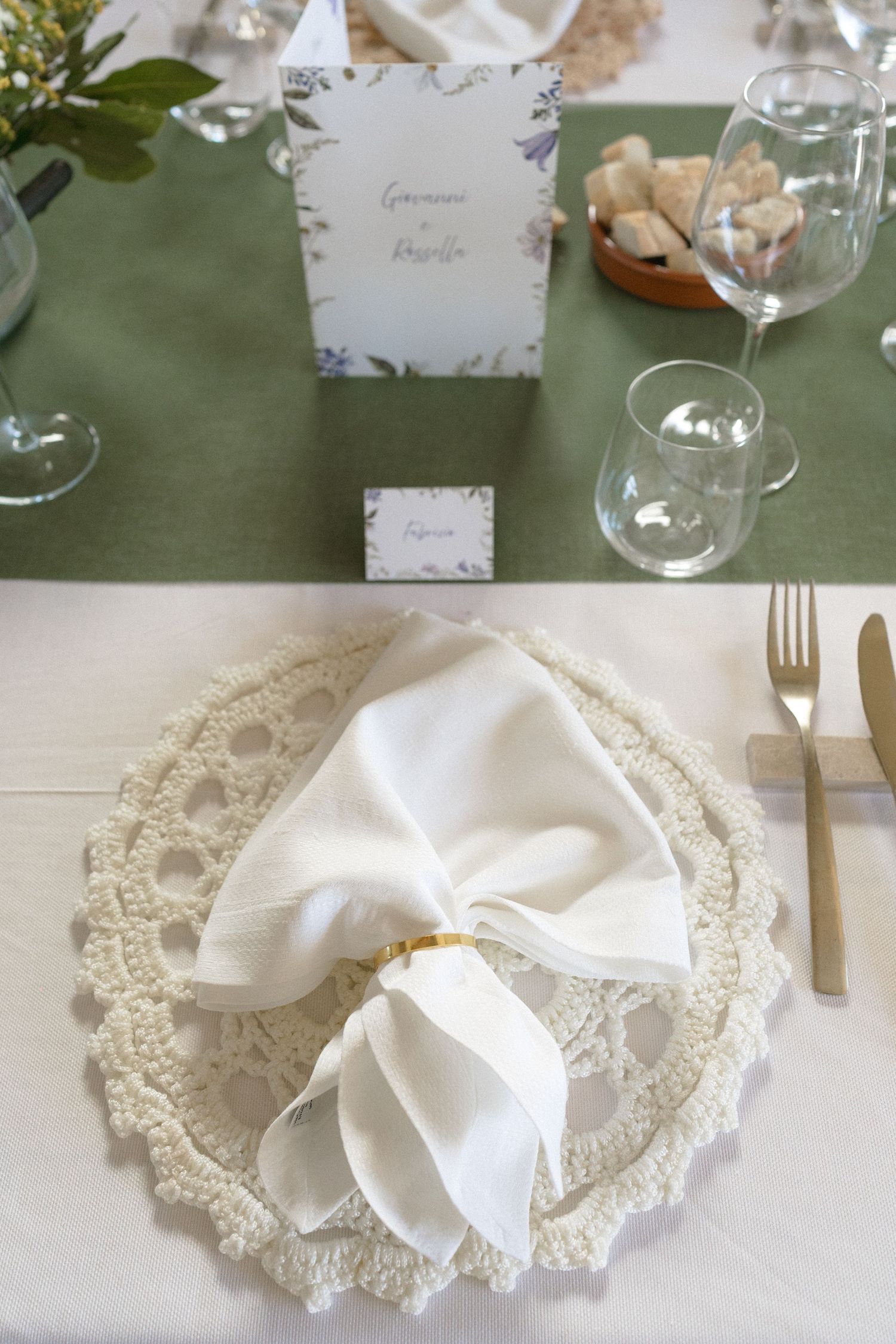 Elegant table settings with white lace napkins and glassware on a sage green tablecloth.