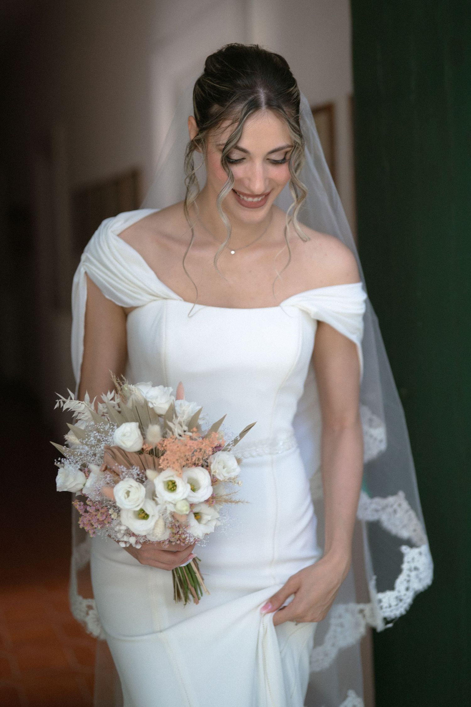 A bride in a classic white wedding dress holds a delicate bouquet of white and blush flowers.