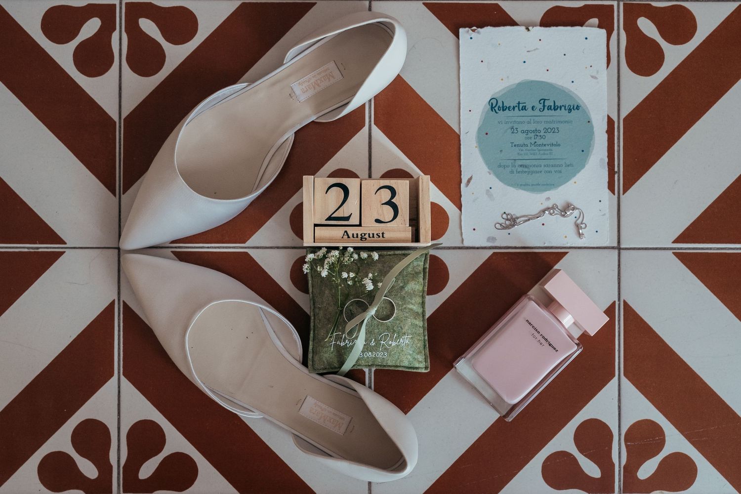 Wedding details flatlay with white shoes and date blocks on geometric tile.