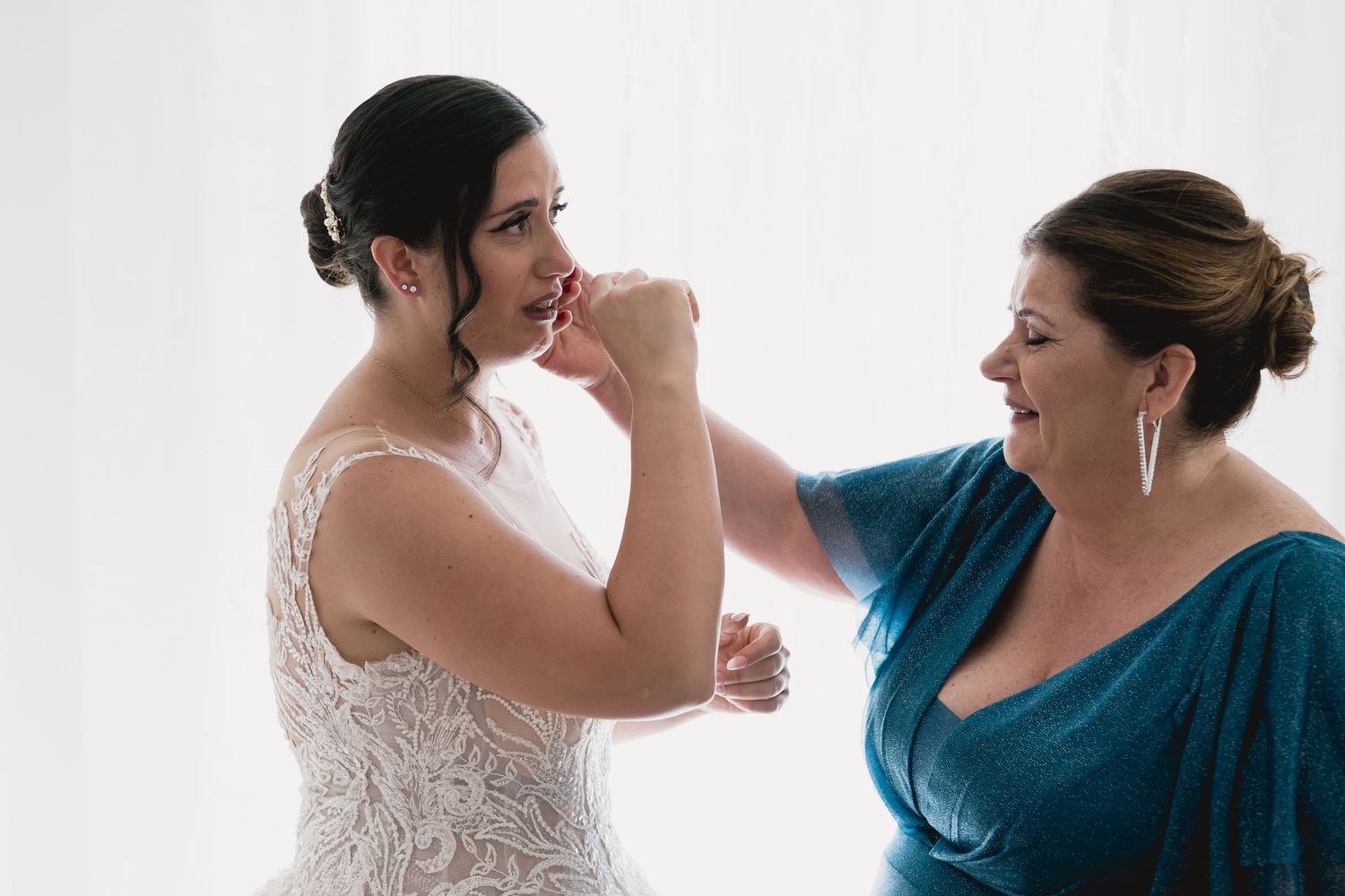 Two people sharing an emotional moment during wedding preparations in a bright room.