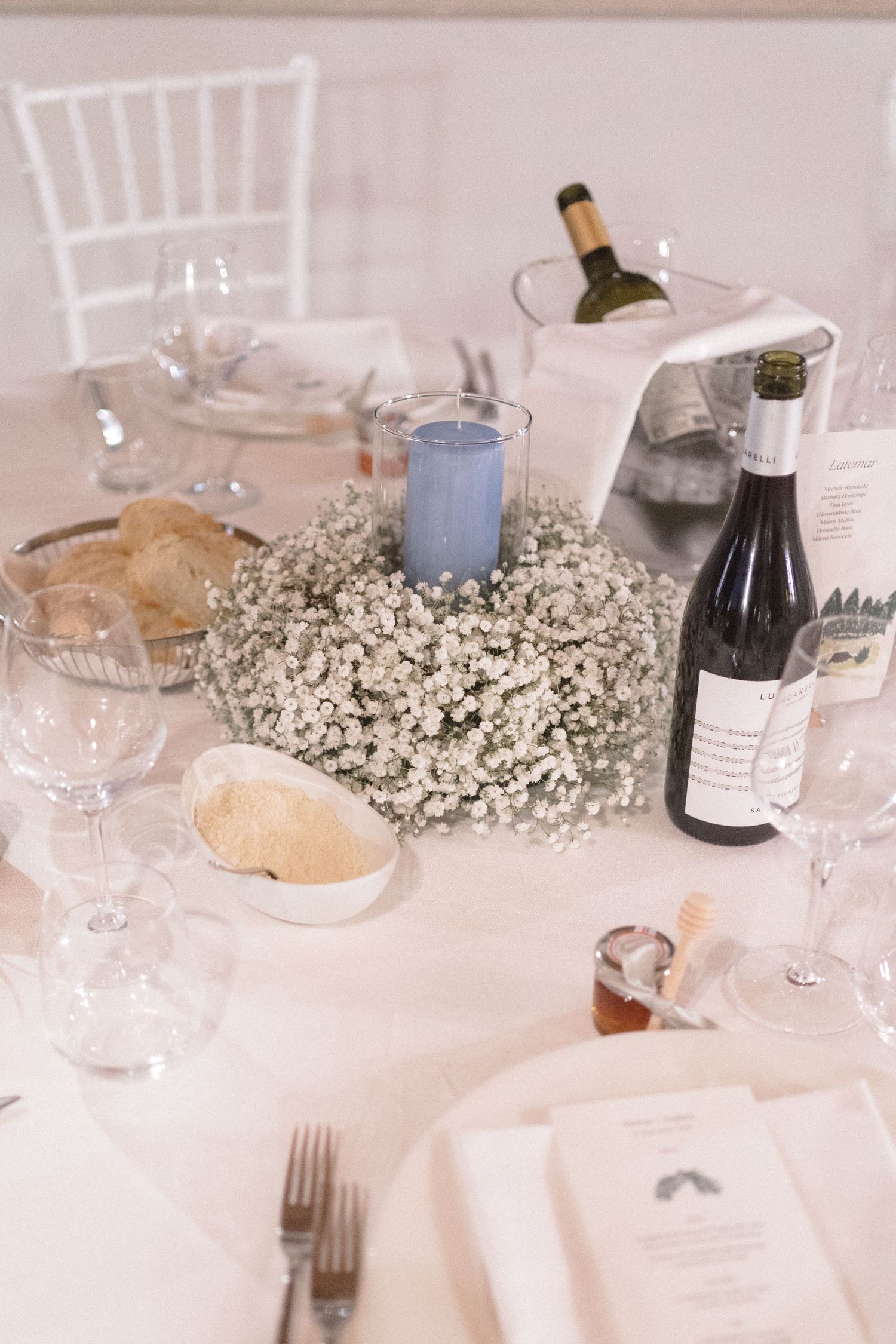 Elegant wedding table settings with white linens, baby's breath centerpieces, and wine glasses.
