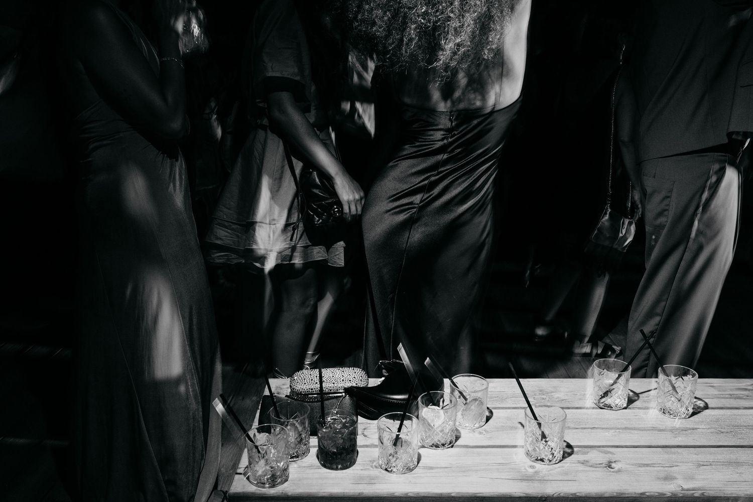Black and white photo of wedding guests dancing on a dimly lit dance floor.